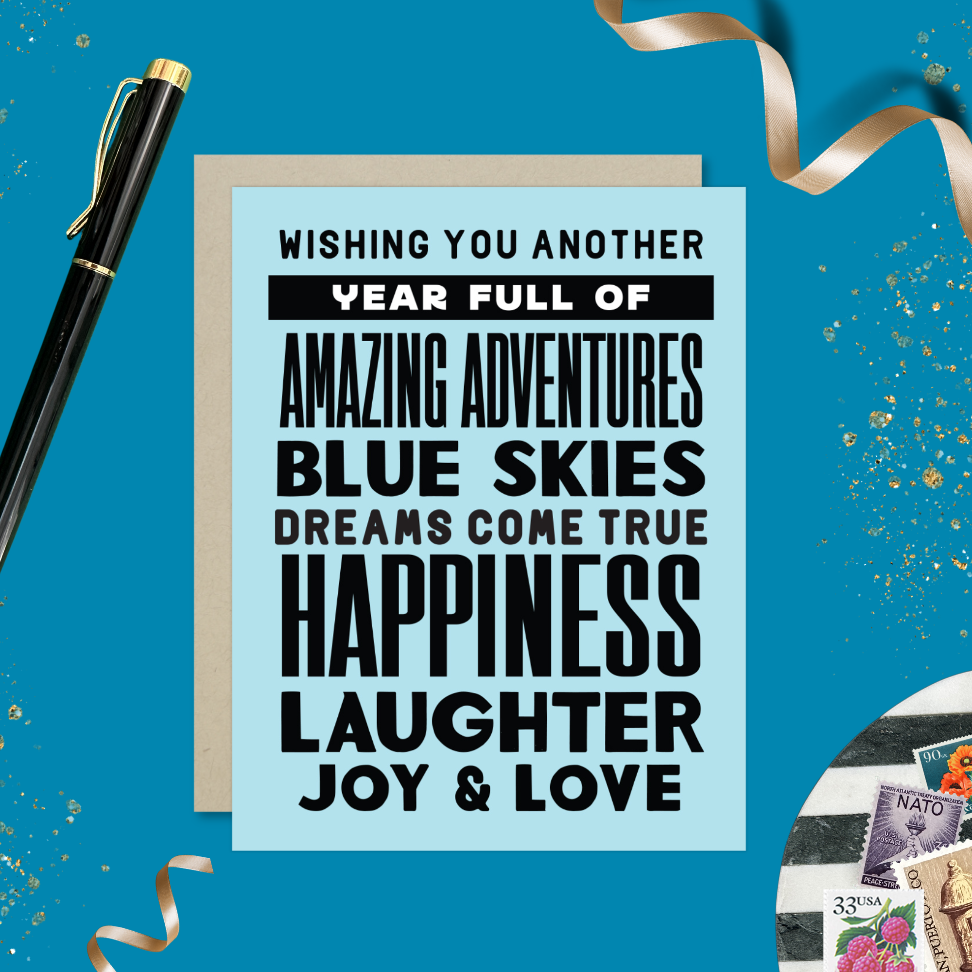 A birthday greeting card with blue background and black text, featuring stacked words and phrases like 'amazing adventures', 'blue skies', 'dreams come true', 'happiness', 'laughter', 'joy & love'
