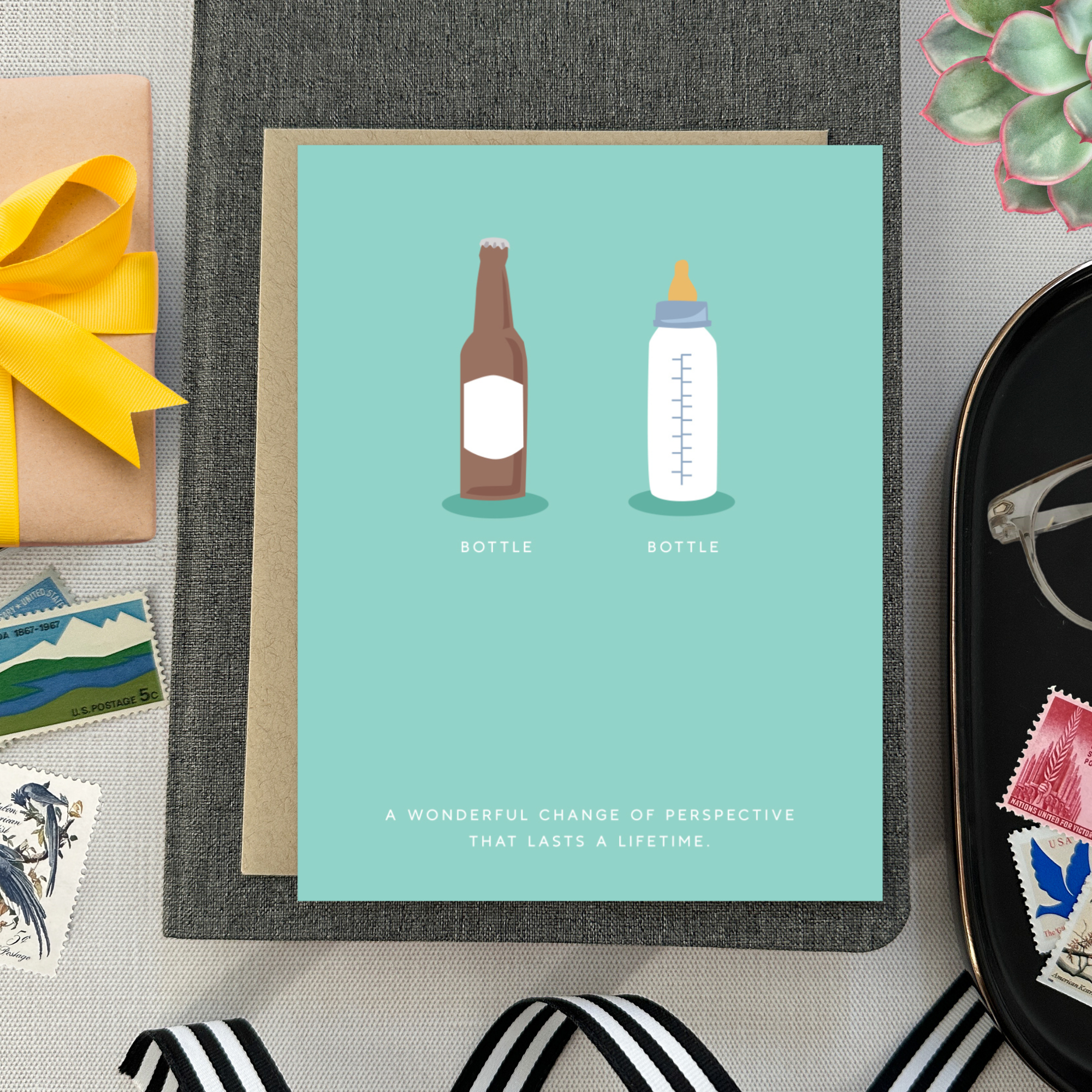 Baby greeting card with beer and baby bottle and 'a wonderful change of perspective that lasts a lifetime' text