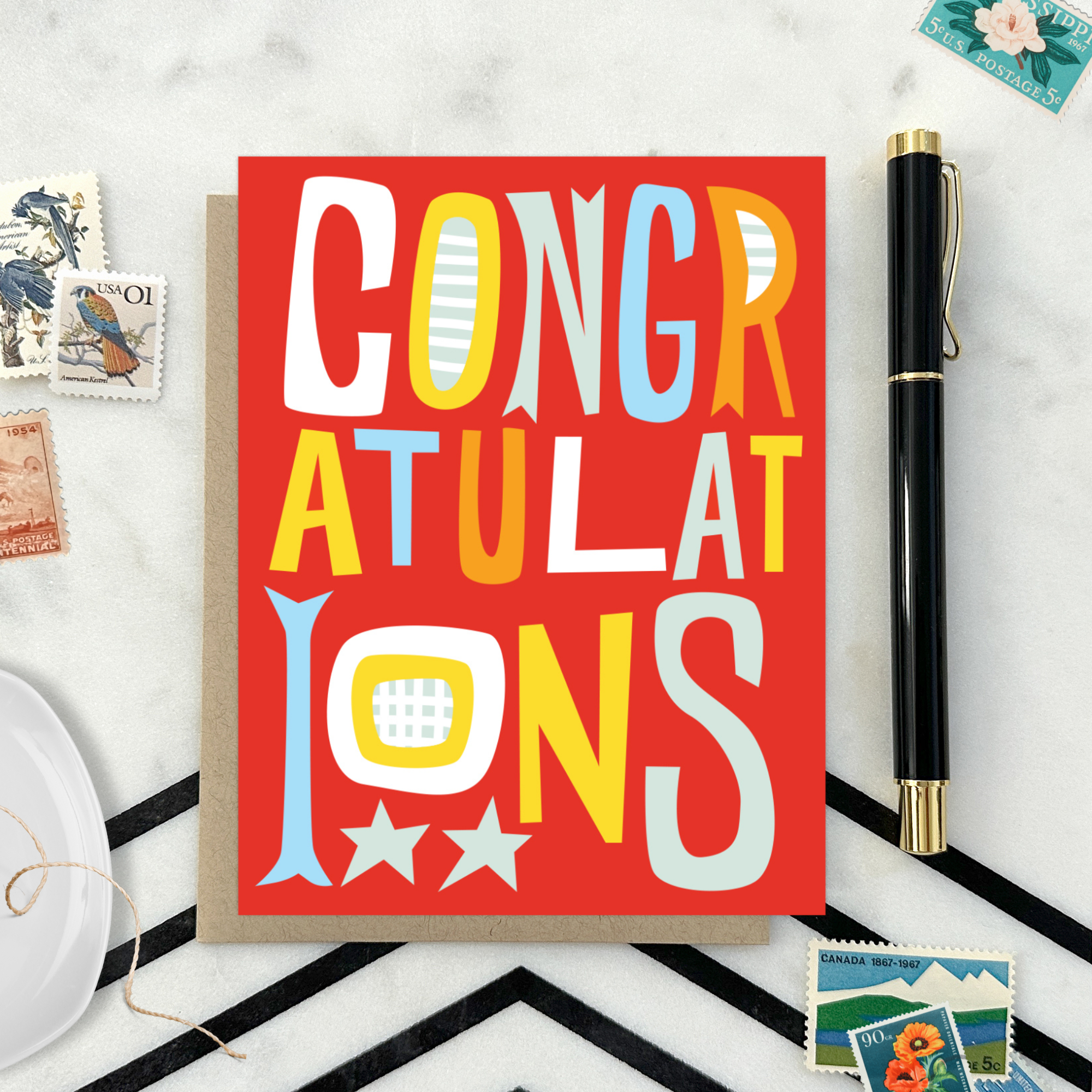 A colorful congratulations greeting card with the word 'CONGRATULATIONS' written in bold, playful lettering, predominantly in red, with additional decorative elements like stars.