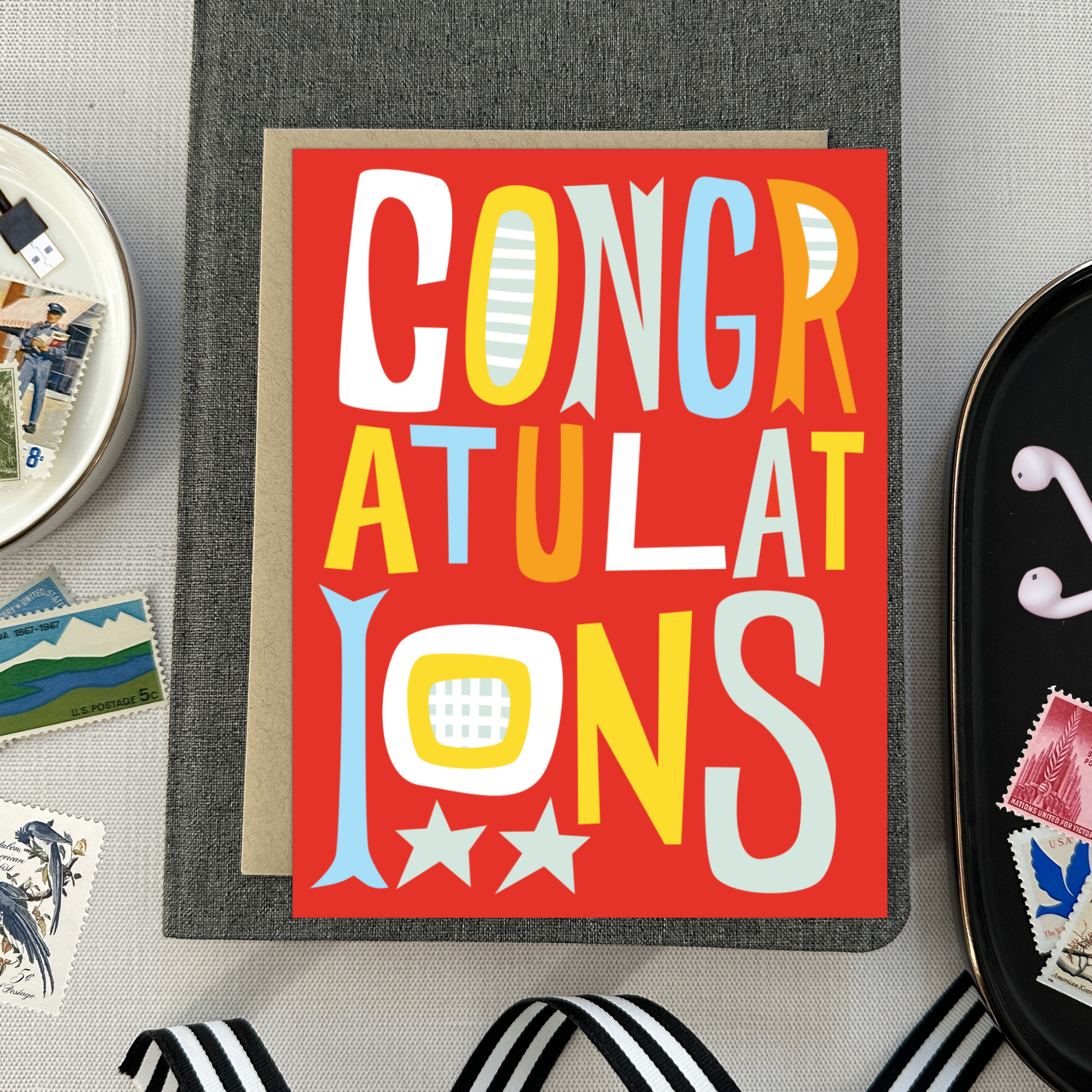 A colorful congratulations greeting card with the word 'CONGRATULATIONS' written in bold, playful lettering, predominantly in red, with additional decorative elements like stars.