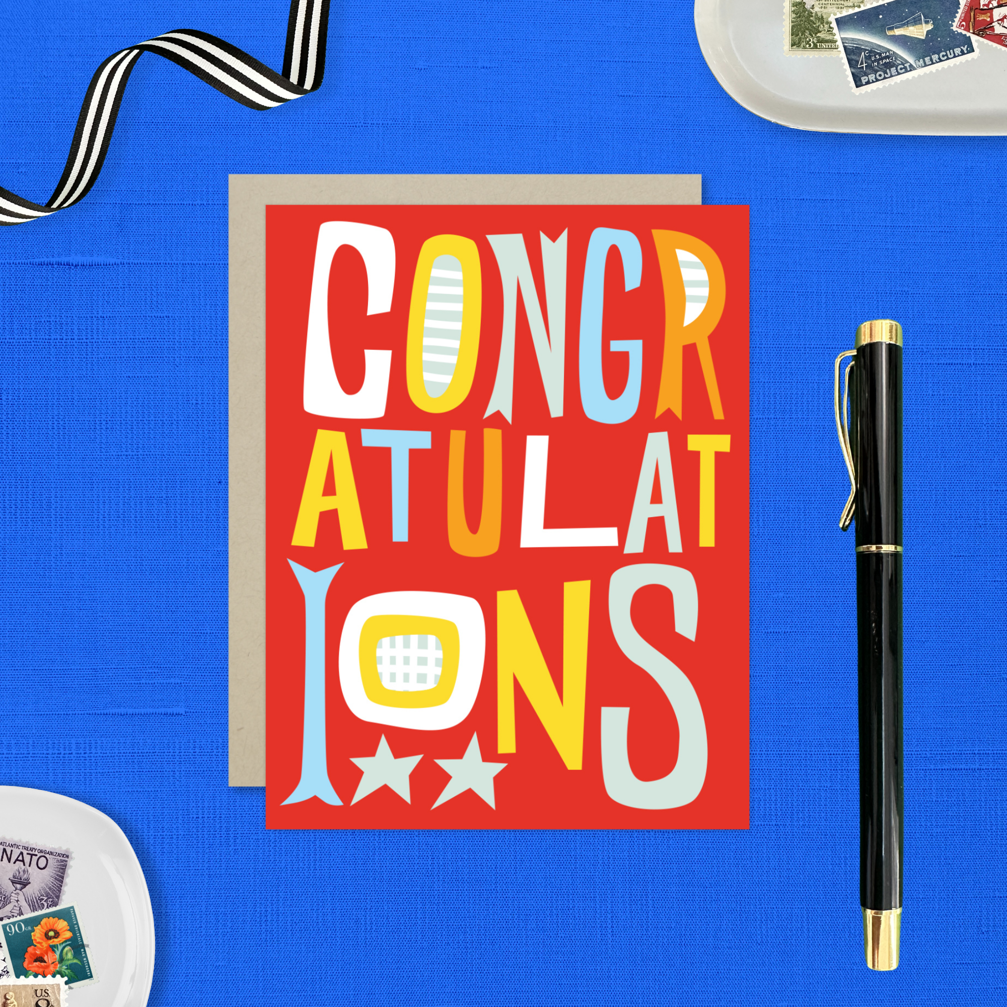 A colorful congratulations greeting card with the word 'CONGRATULATIONS' written in bold, playful lettering, predominantly in red, with additional decorative elements like stars.