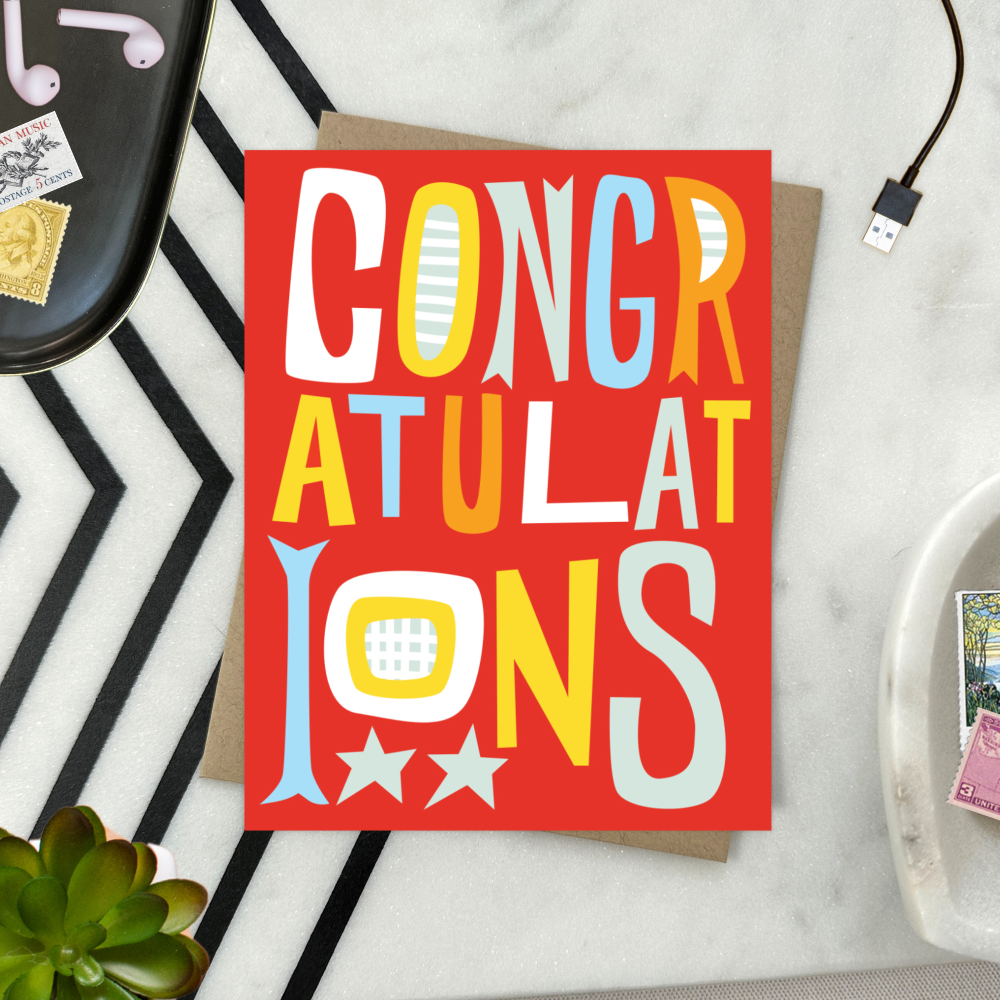 A colorful congratulations greeting card with the word 'CONGRATULATIONS' written in bold, playful lettering, predominantly in red, with additional decorative elements like stars.