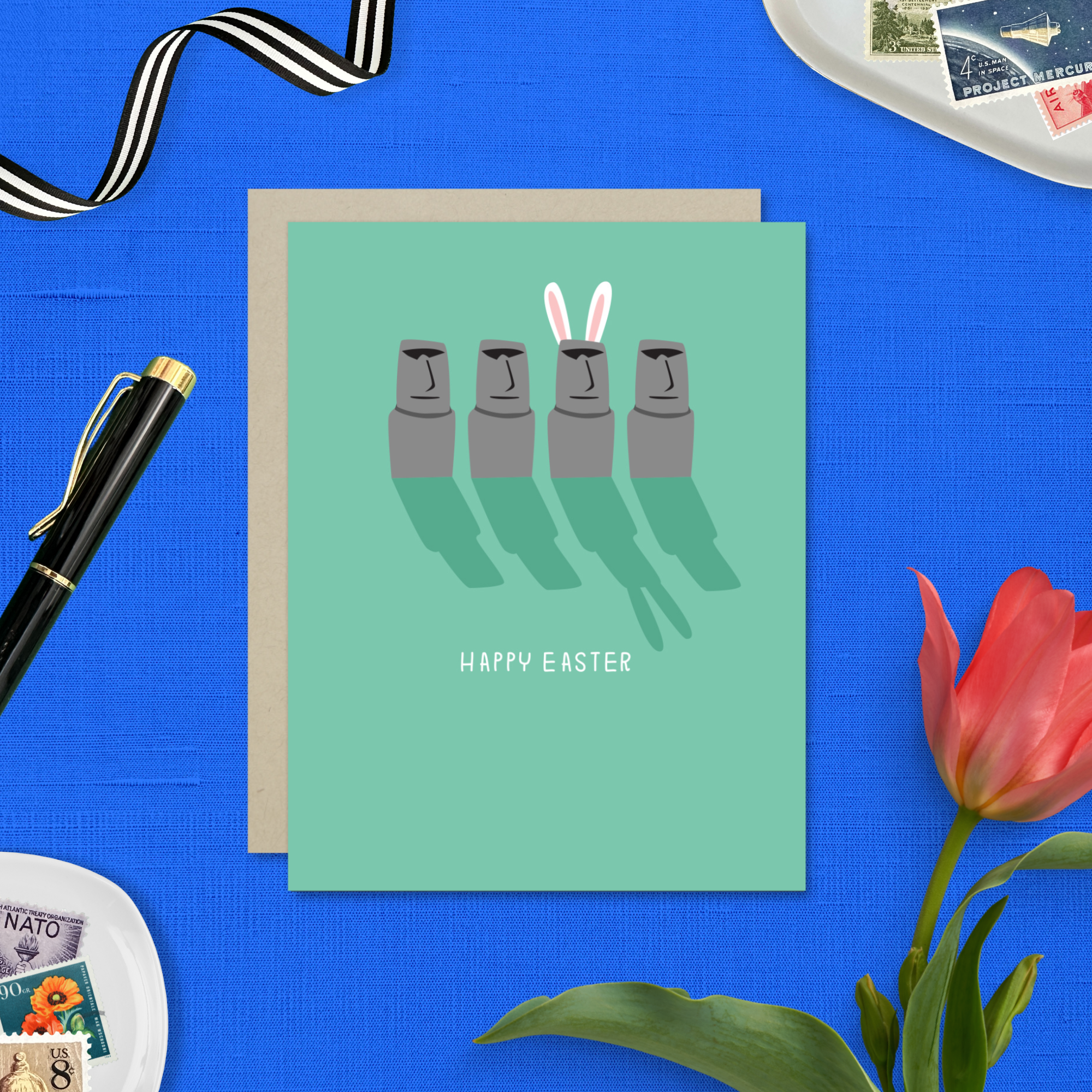 Easter greeting card with Easter island heads, one is wearing bunny ears with 'happy easter' text