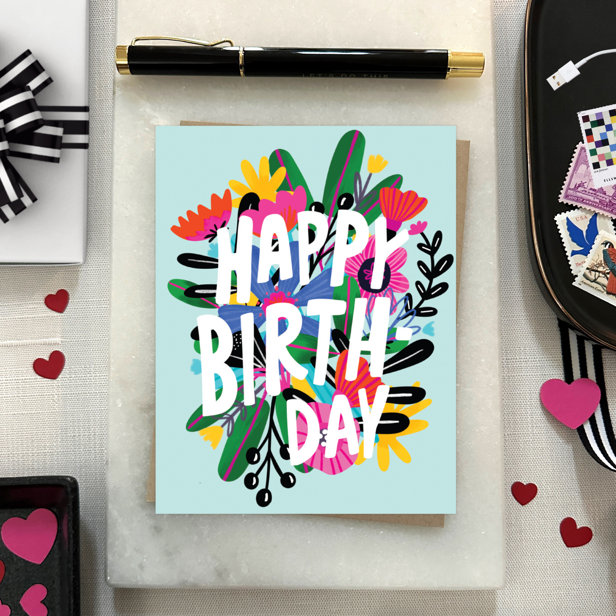 A colorful birthday greeting card with a floral design and the text 'HAPPY BIRTHDAY' on a light blue background.