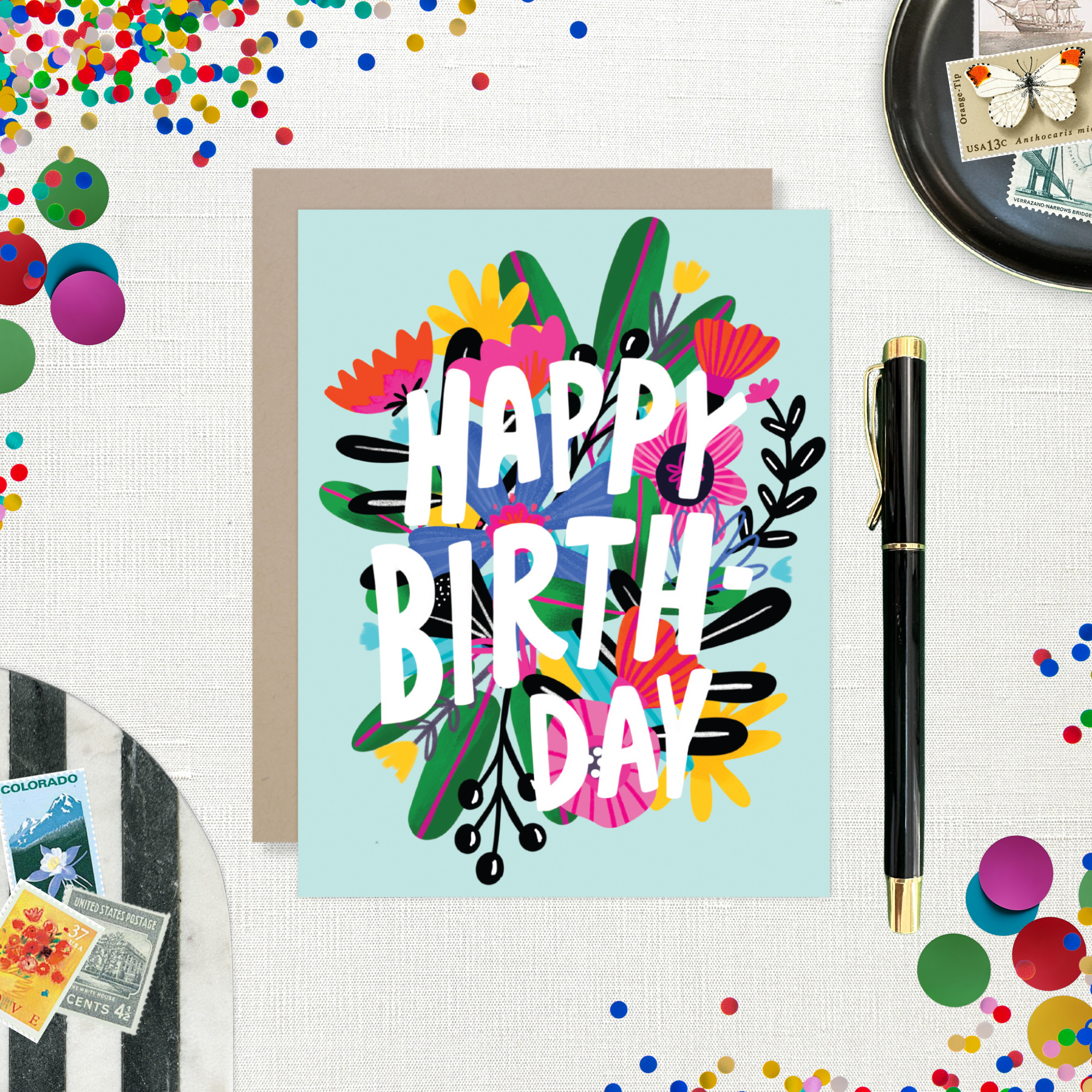 A colorful birthday greeting card with a floral design and the text 'HAPPY BIRTHDAY' on a light blue background.