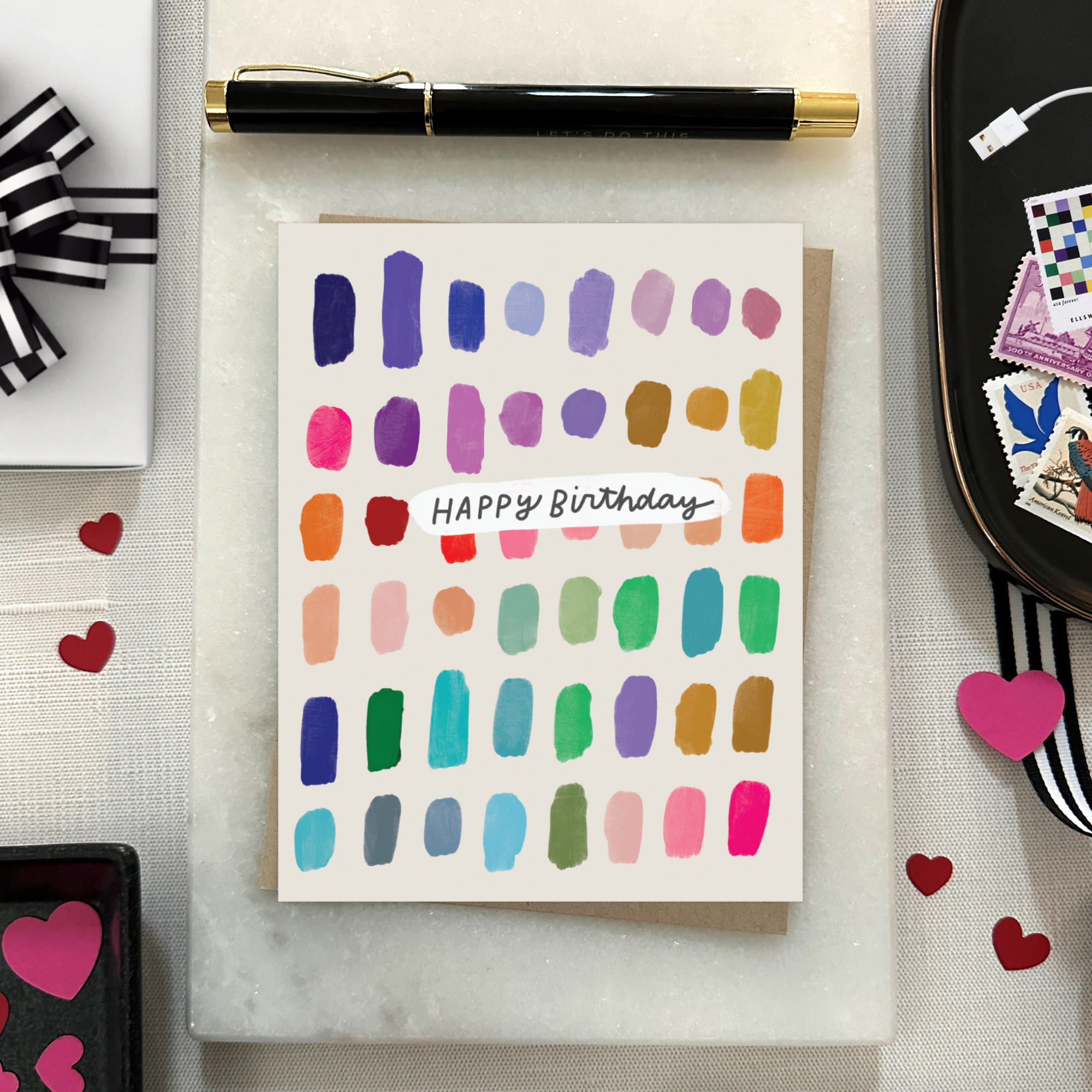 A colorful birthday card with paint swatch-like designs in various colors and the text 'Happy Birthday' on it.