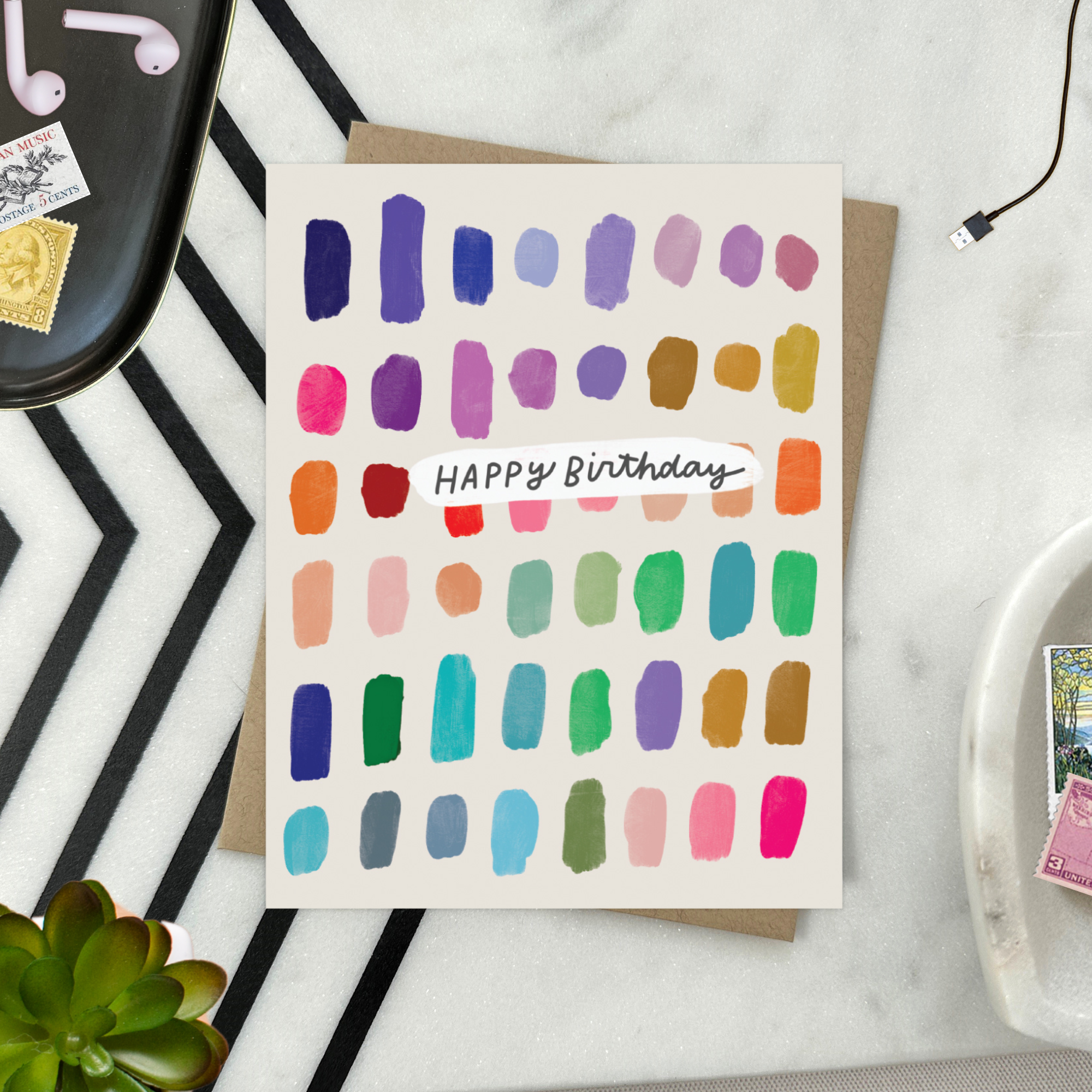 A colorful birthday card with paint swatch-like designs in various colors and the text 'Happy Birthday' on it.