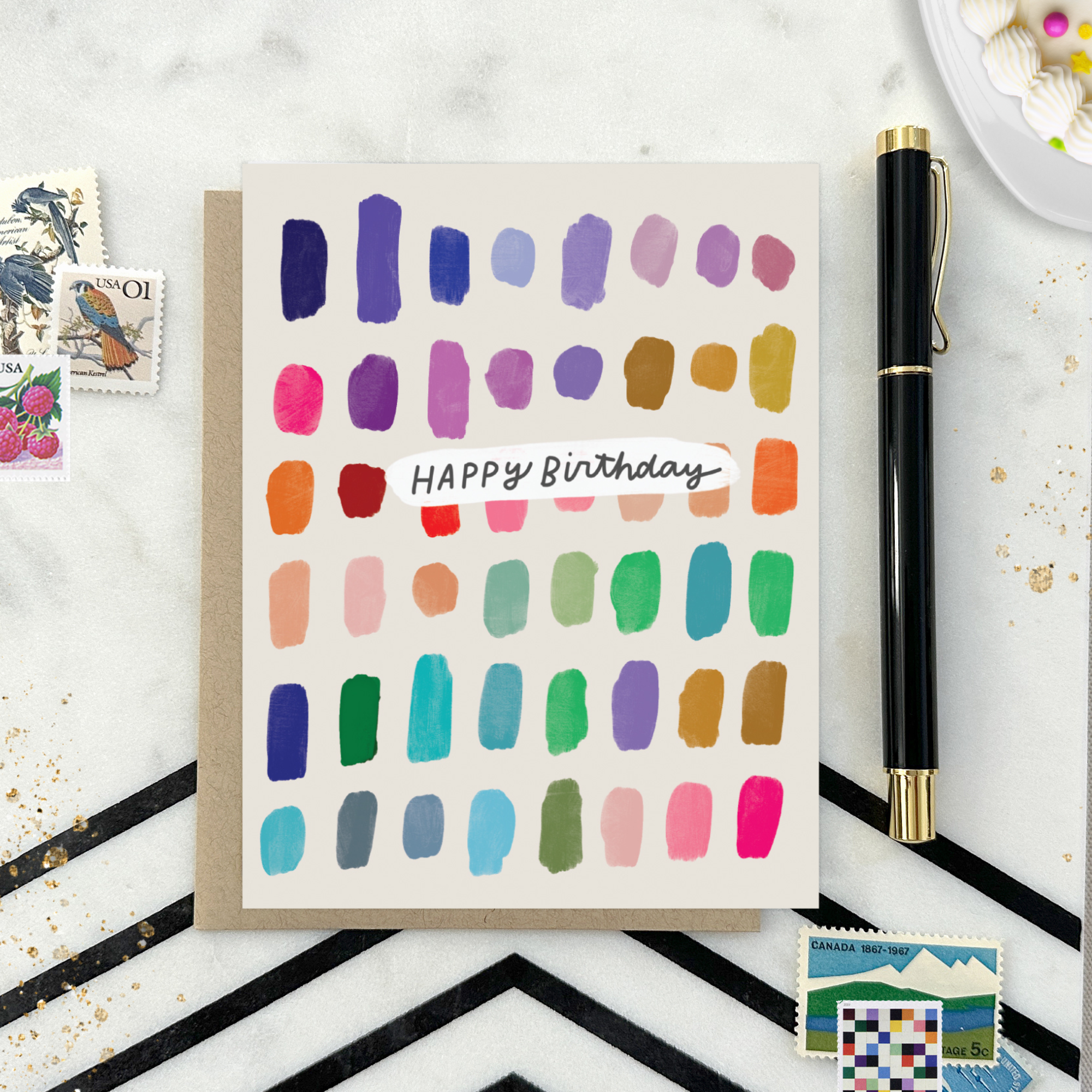 A colorful birthday card with paint swatch-like designs in various colors and the text 'Happy Birthday' on it.