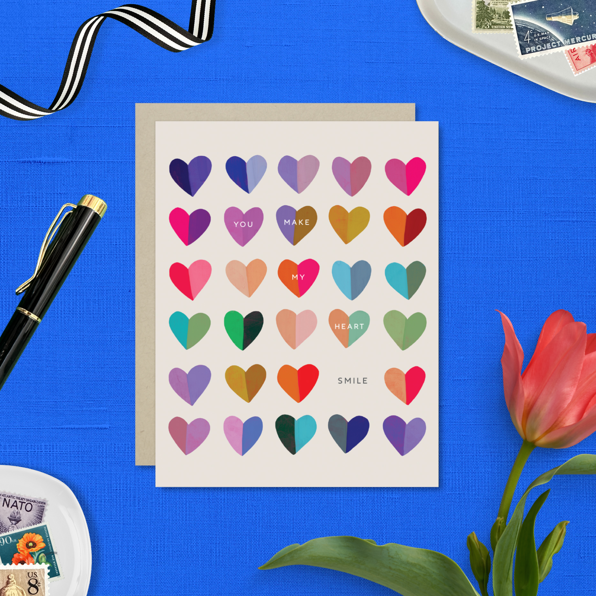 A valentines day greeting card with a cheerful grid of colorful hearts and the message 'You make my heart smile' written on it.