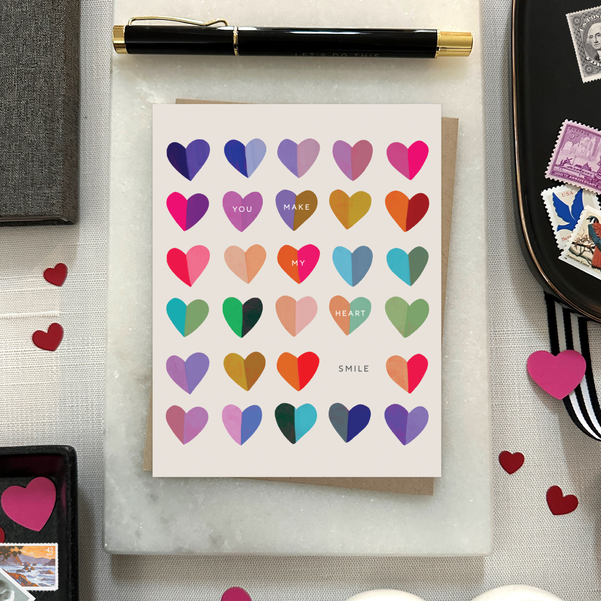 A valentines day greeting card with a cheerful grid of colorful hearts and the message 'You make my heart smile' written on it.
