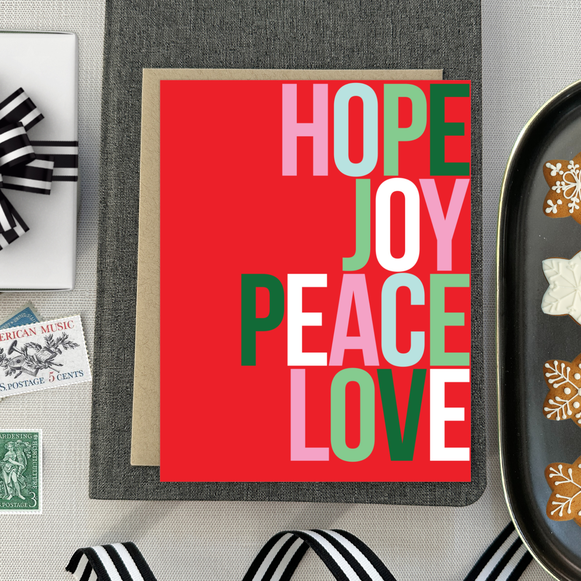 A red holiday greeting card with the words 'HOPE, JOY, PEACE, LOVE' stacked in a graphic design.