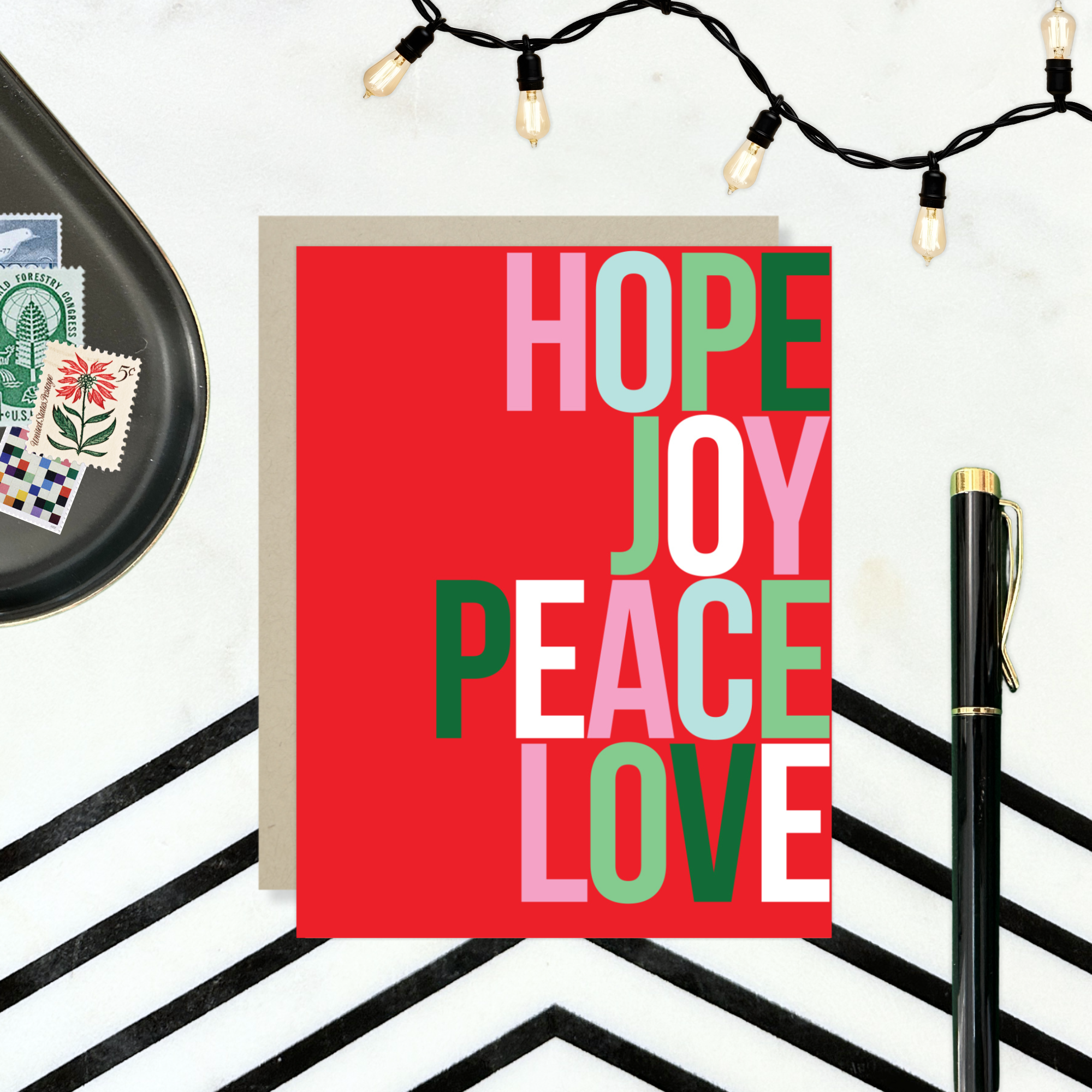 A red holiday greeting card with the words 'HOPE, JOY, PEACE, LOVE' stacked in a graphic design.