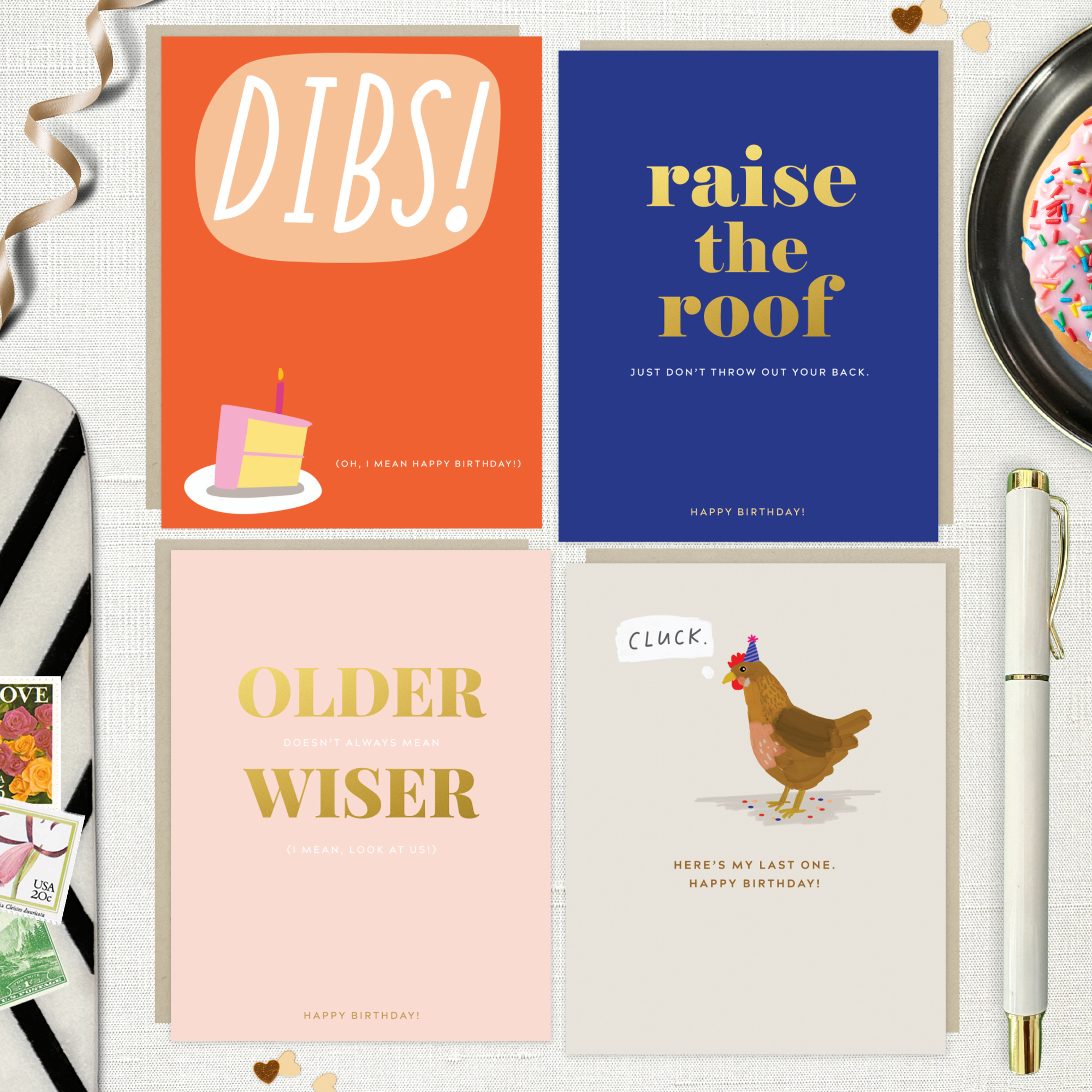 4-pack of funny birthday cards created by Barone & Co. featuring a chicken's last cluck, raise the roof but don't throw your back out, older but not wiser, and dibs on your birthday cake on white linen background with ribbons and confetti