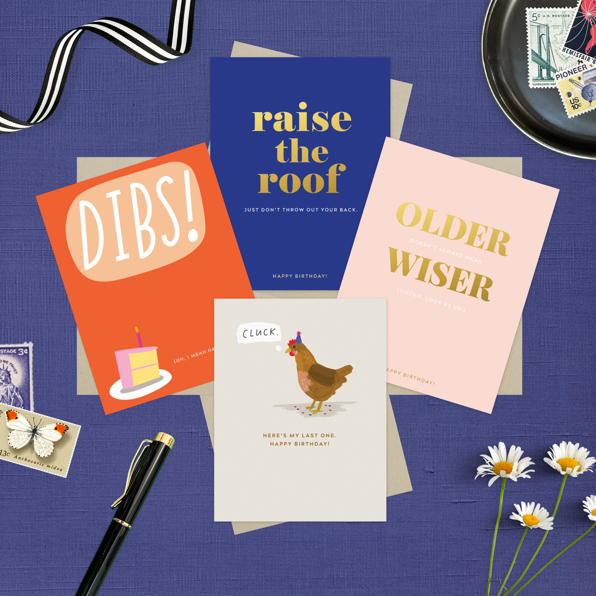 4-pack of funny birthday cards created by Barone & Co. featuring a chicken's last cluck, raise the roof but don't throw your back out, older but not wiser, and dibs on your birthday cake on a dark purple background with stamps and flowers