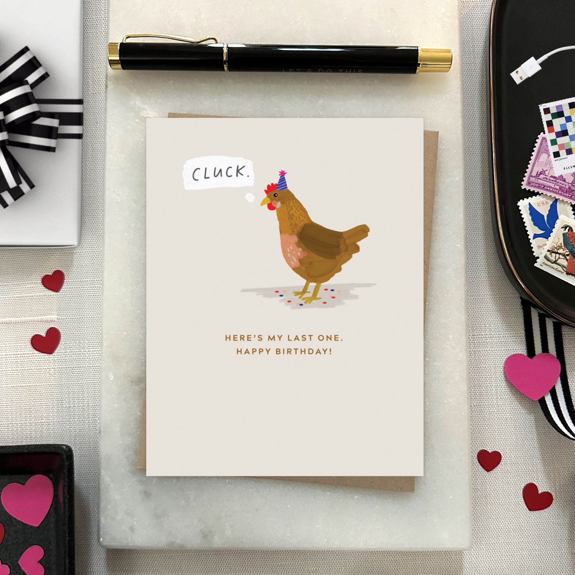 A funny birthday greeting card with an illustration of a chicken wearing a birthday hat, with the text 'Cluck. Here's my last one'