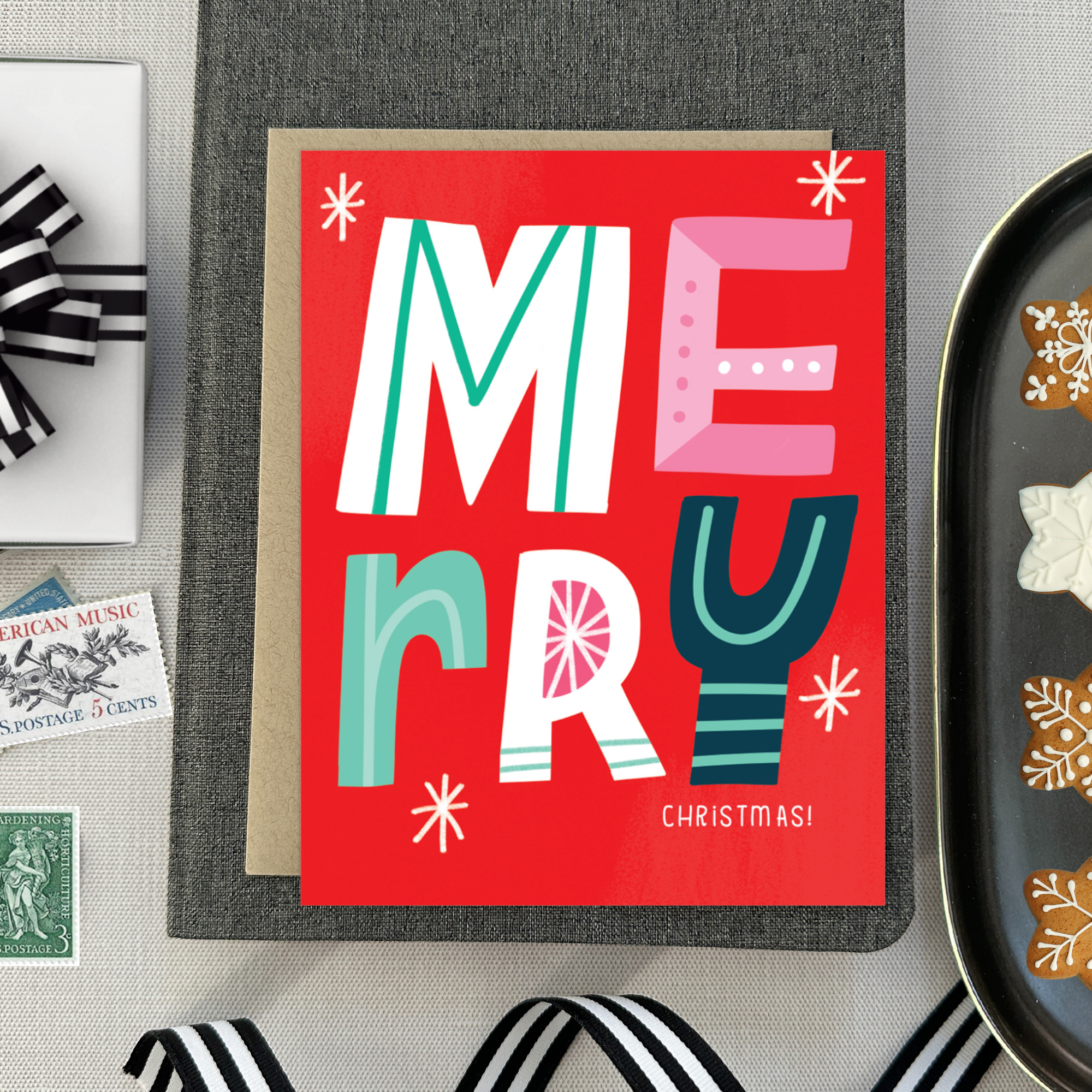 A festive Christmas greeting card with the word 'Merry' written in colorful, decorative lettering on a red background, with 'Christmas' written below.