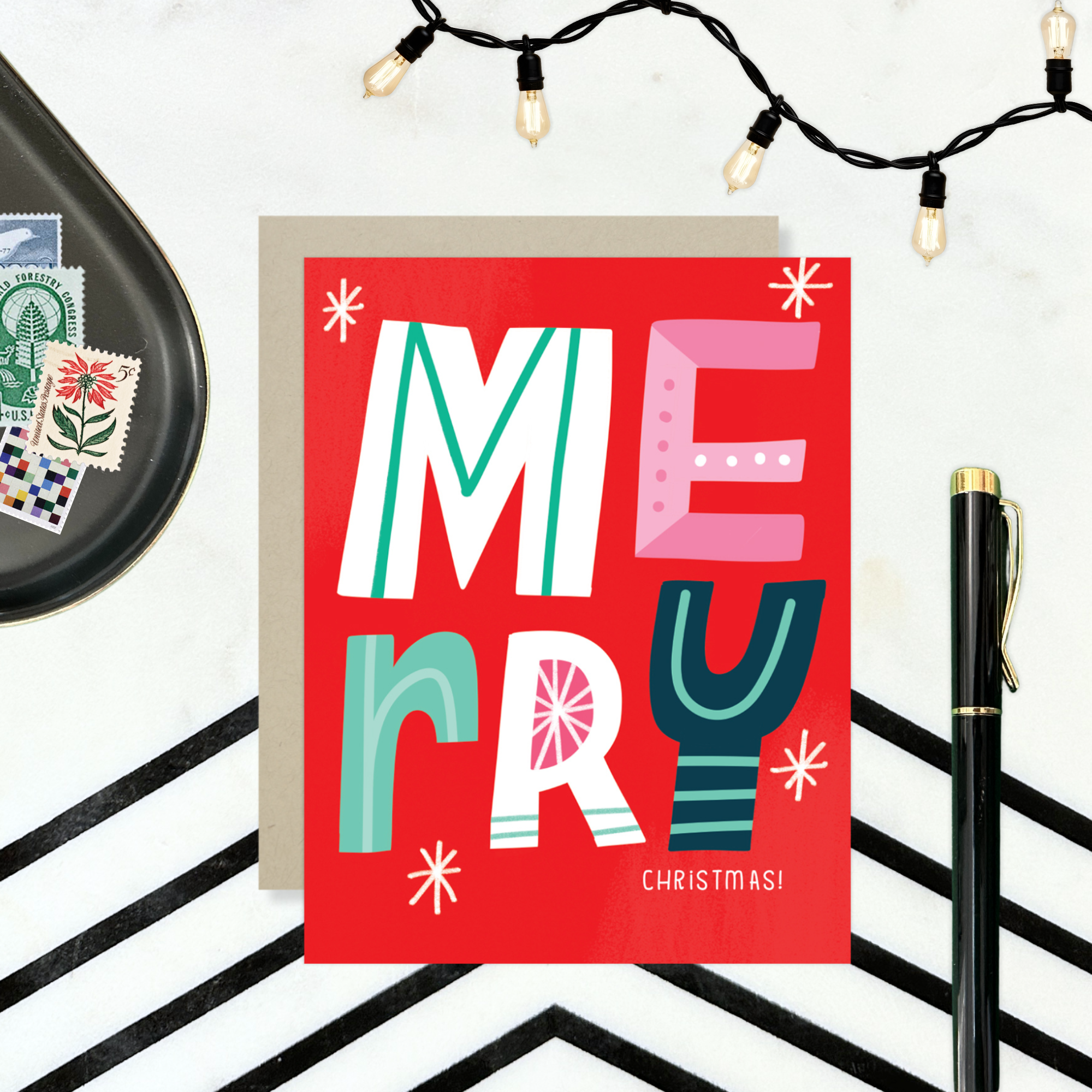 A festive Christmas greeting card with the word 'Merry' written in colorful, decorative lettering on a red background, with 'Christmas' written below.