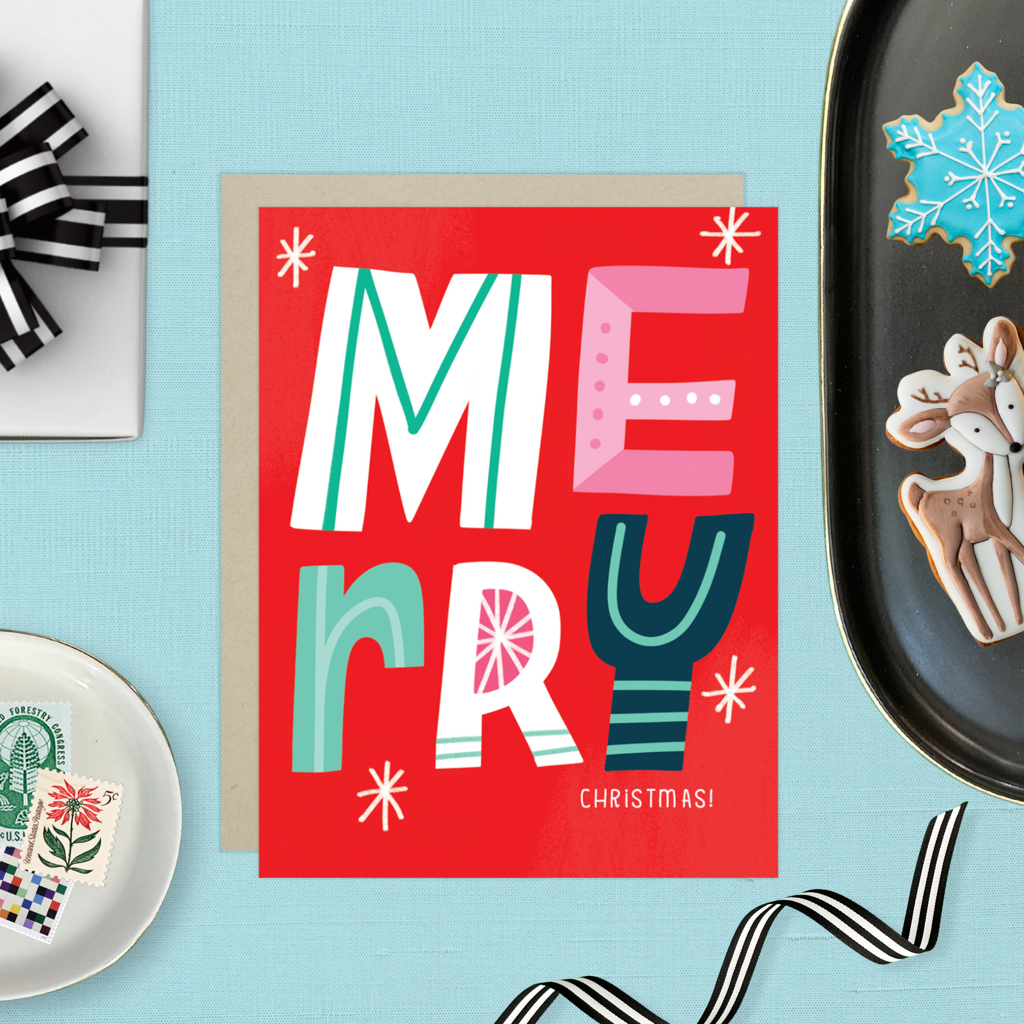 A festive Christmas greeting card with the word 'Merry' written in colorful, decorative lettering on a red background, with 'Christmas' written below.
