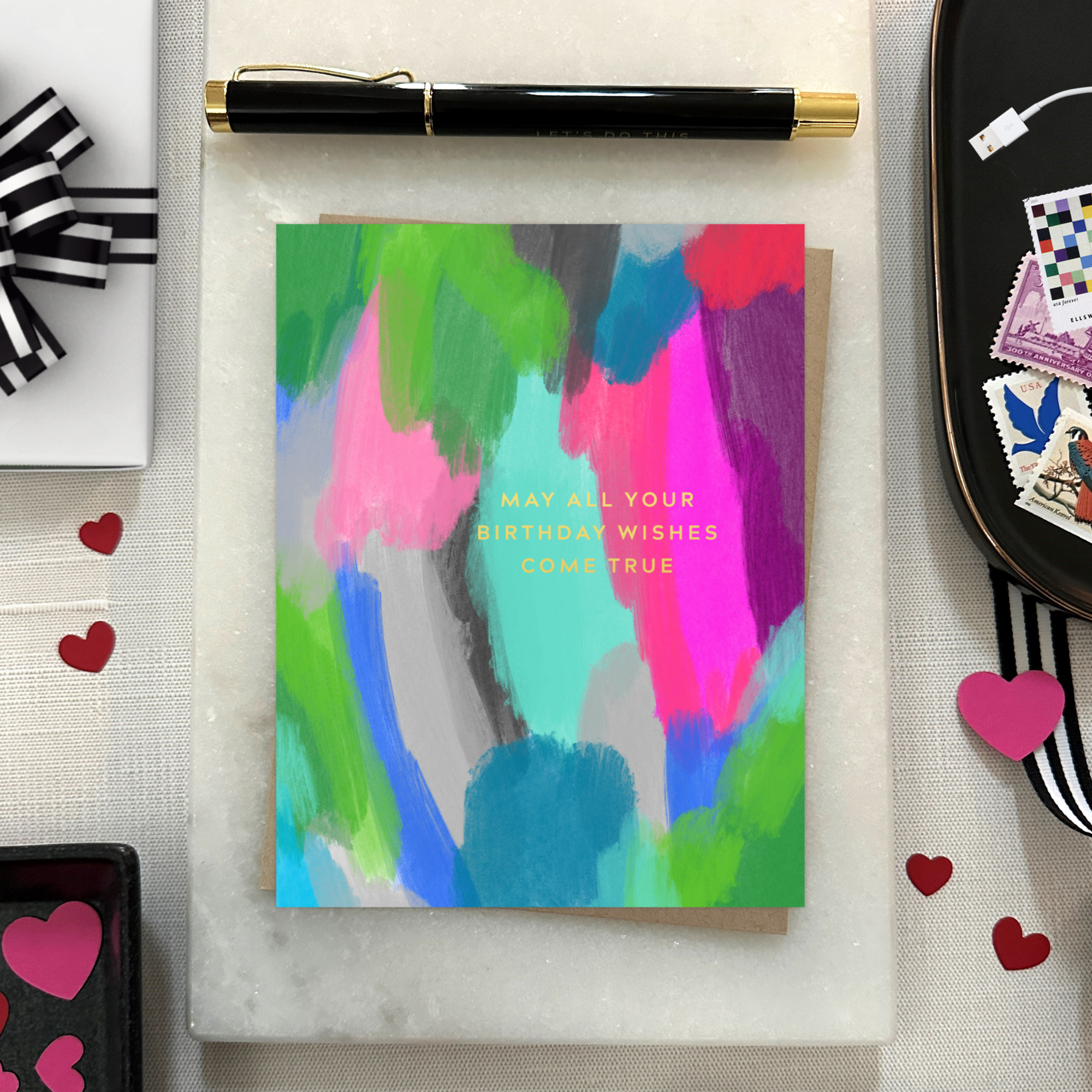 A colorful birthday greeting card with a hand-painted abstract design and gold foil lettering that reads 'May All Your Birthday Wishes Come True'.