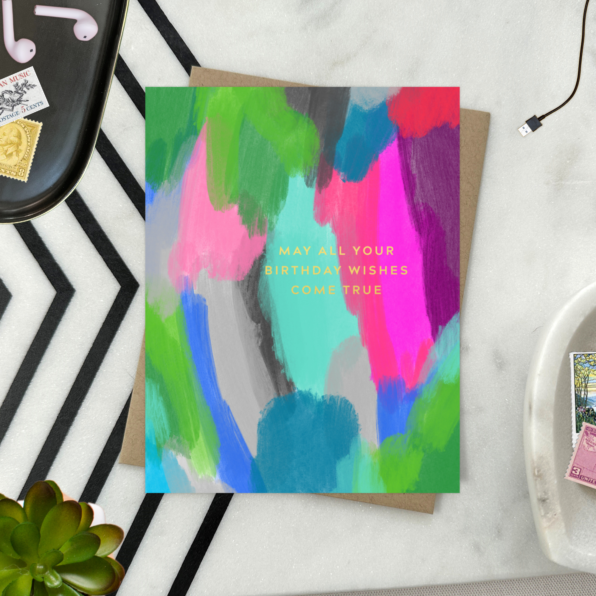A colorful birthday greeting card with a hand-painted abstract design and gold foil lettering that reads 'May All Your Birthday Wishes Come True'.