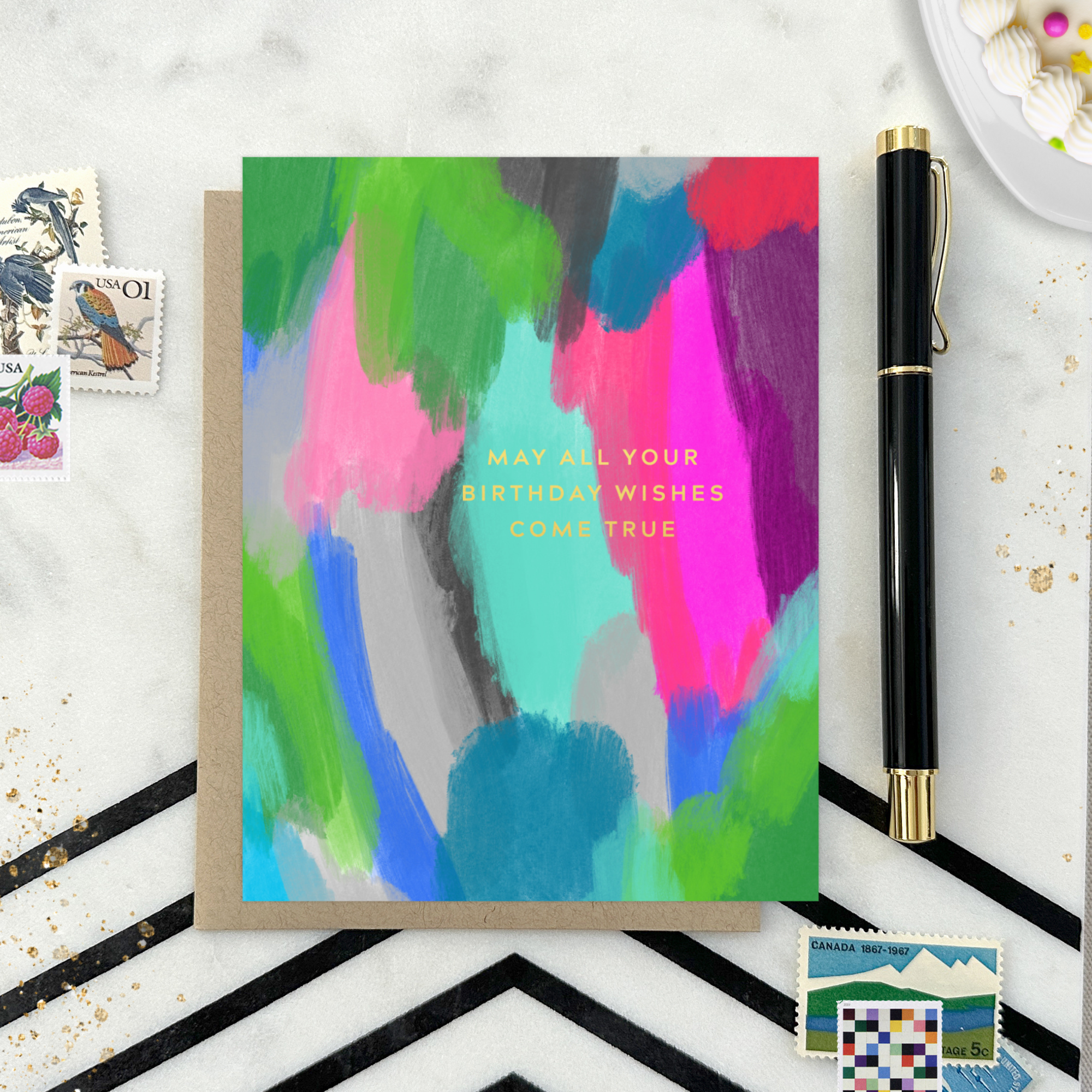 A colorful birthday greeting card with a hand-painted abstract design and gold foil lettering that reads 'May All Your Birthday Wishes Come True'.