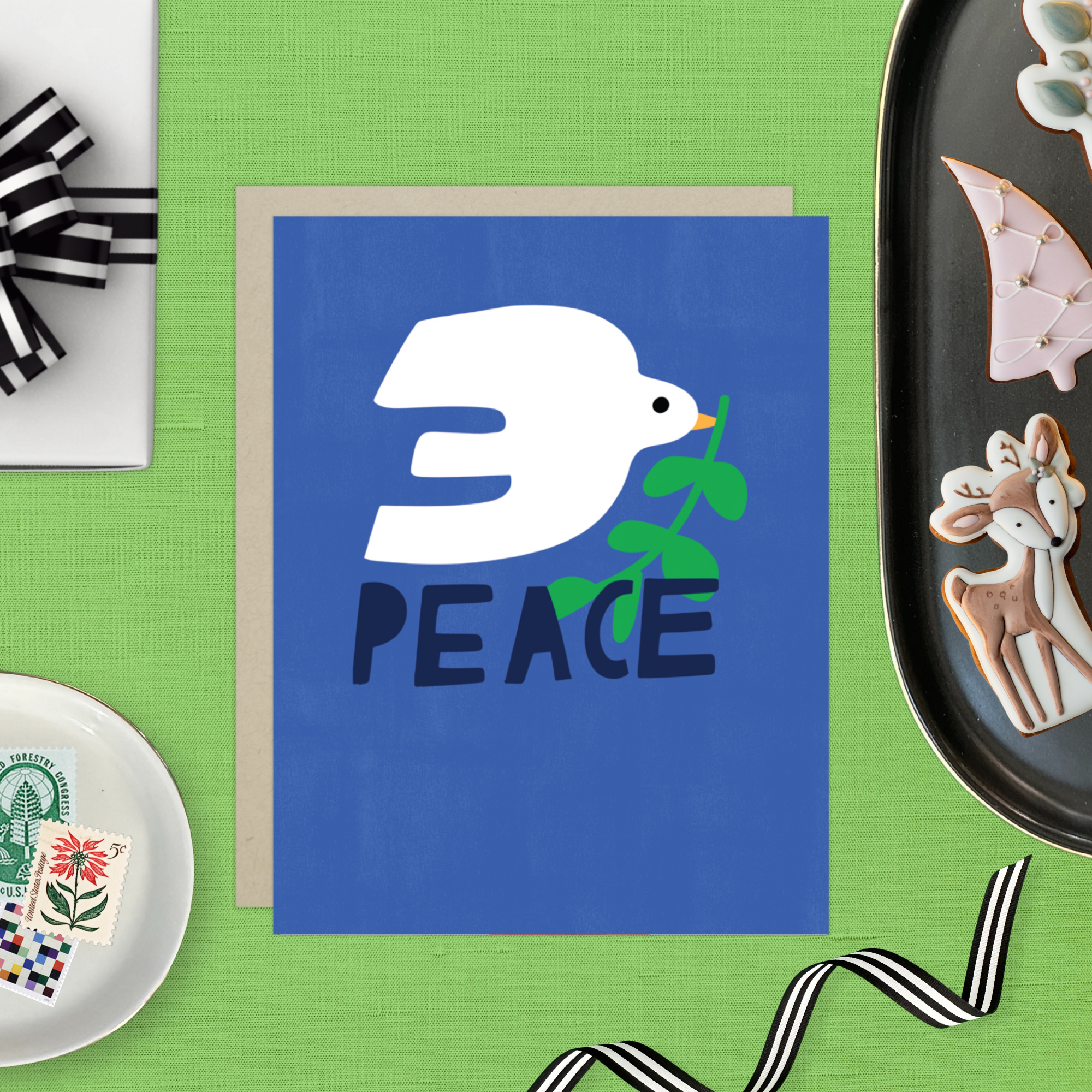 hand-painted holiday reeting card with a blue background featuring a white bird and the word 'PEACE' in capital letters.