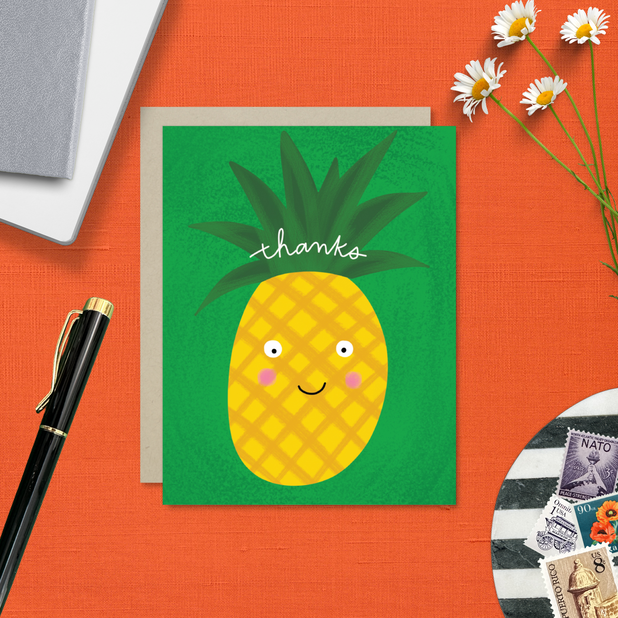 A playful thank you greeting card with a green background featuring a happy illustrated pineapple with the text 'thanks' written on it.