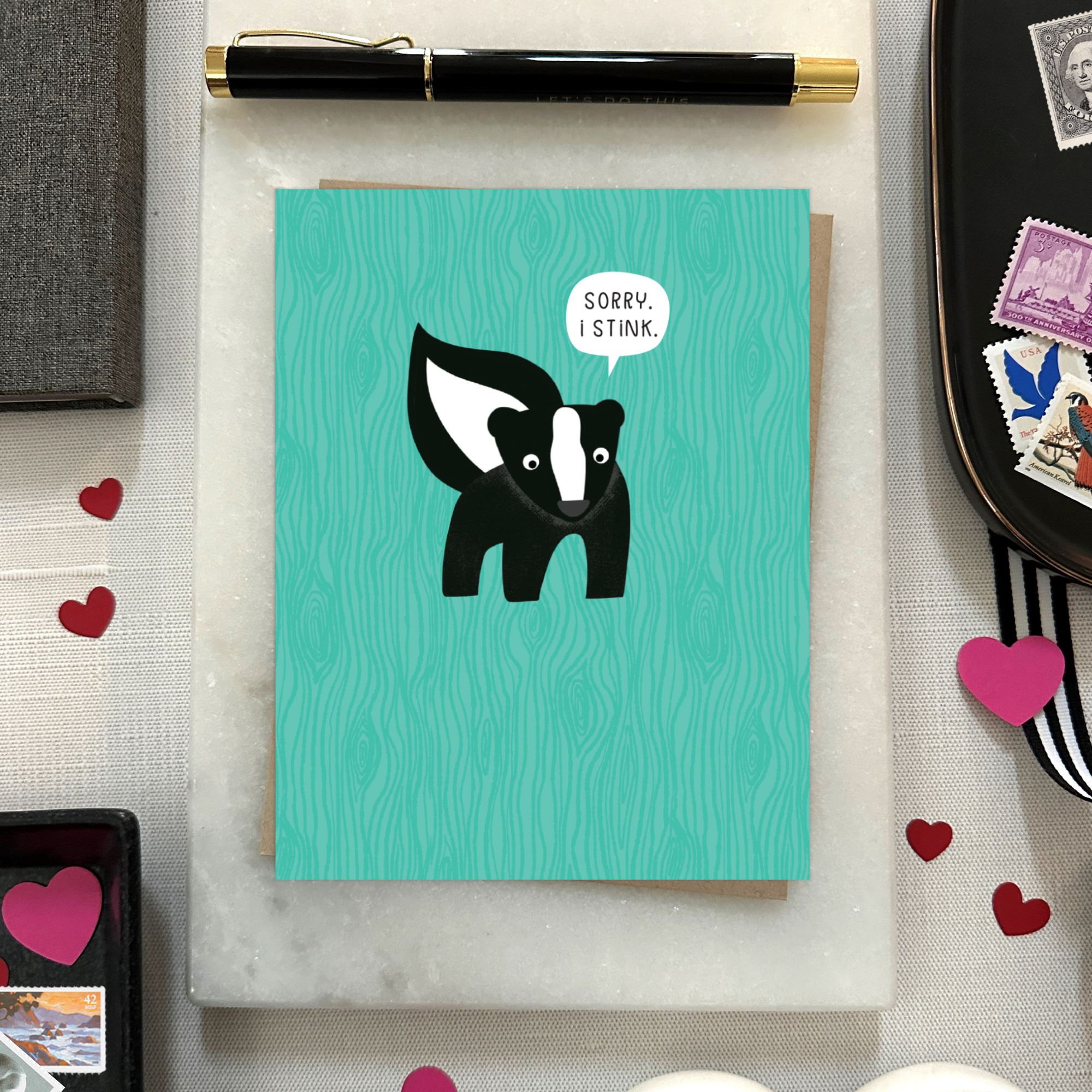 A sorry greeting card with an illustration of a skunk and the text 'Sorry I Stink' on a teal background.