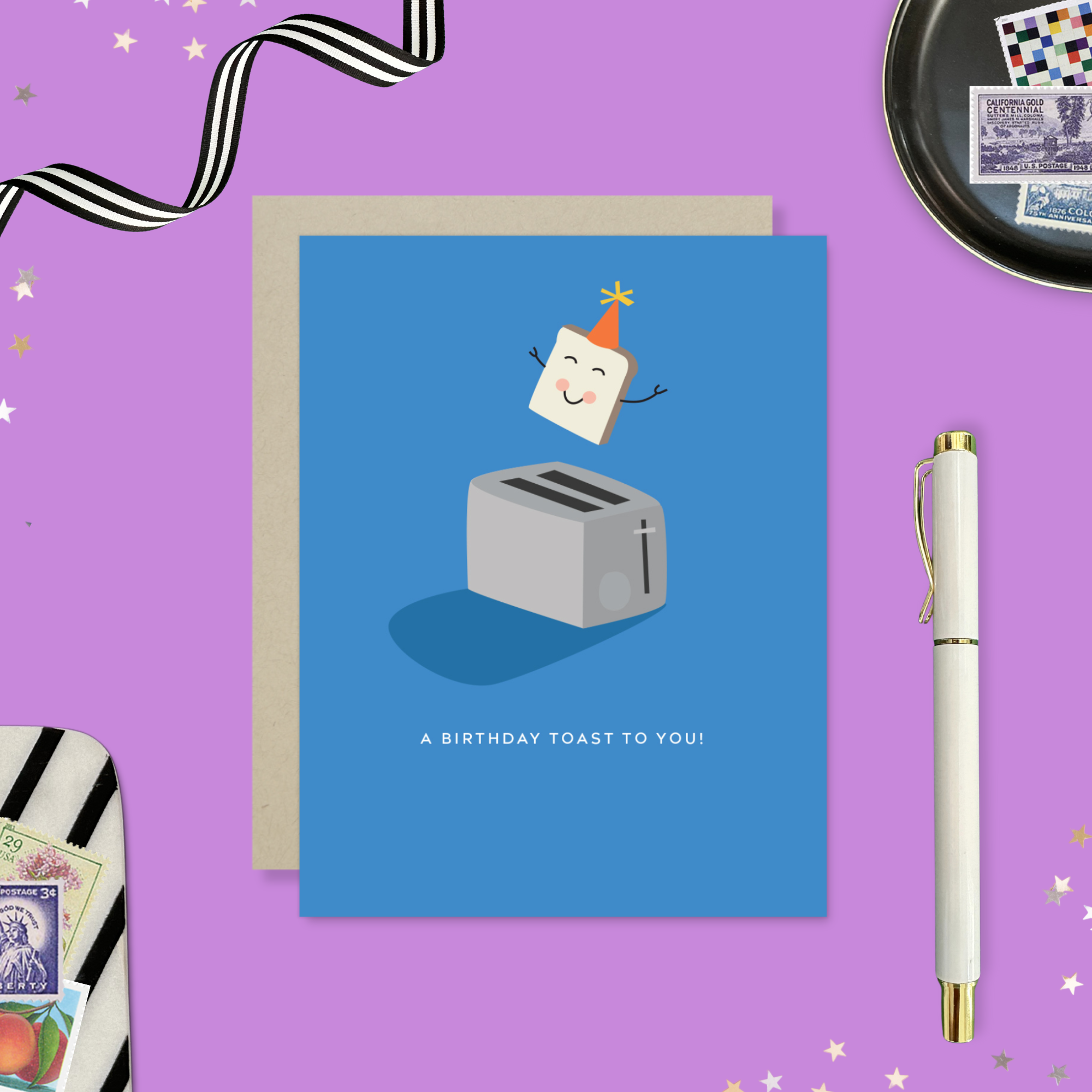 A playful birthday greeting card with an illustration of a smiling slice of toast with a party hat popping out of a toaster, and the text 'A Birthday Toast to You!'.
