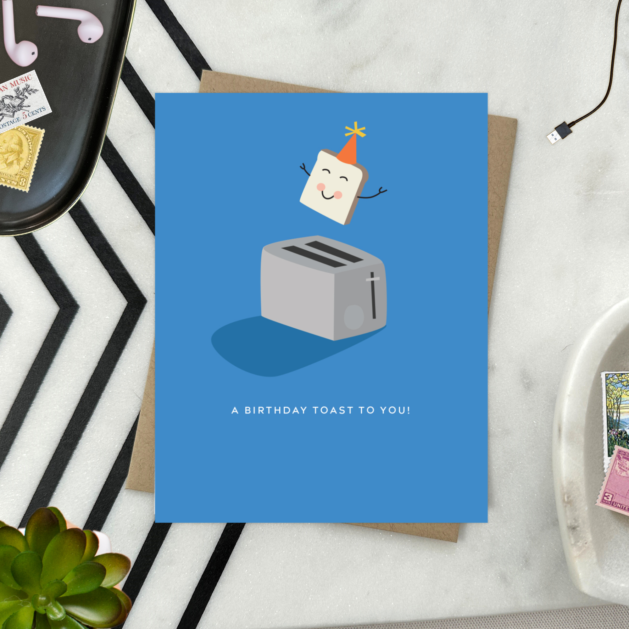 A playful birthday greeting card with an illustration of a smiling slice of toast with a party hat popping out of a toaster, and the text 'A Birthday Toast to You!'.