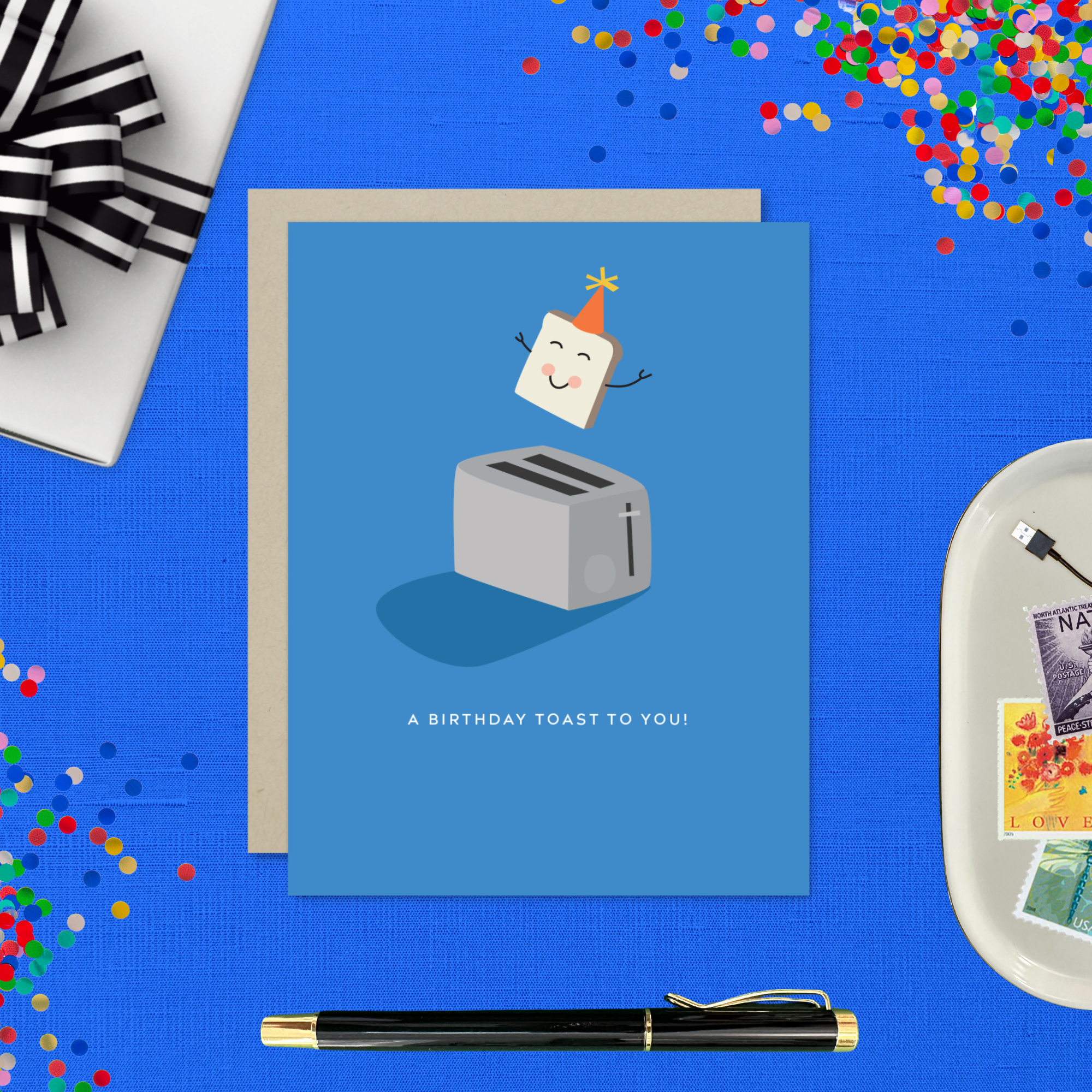 A playful birthday greeting card with an illustration of a smiling slice of toast with a party hat popping out of a toaster, and the text 'A Birthday Toast to You!'.