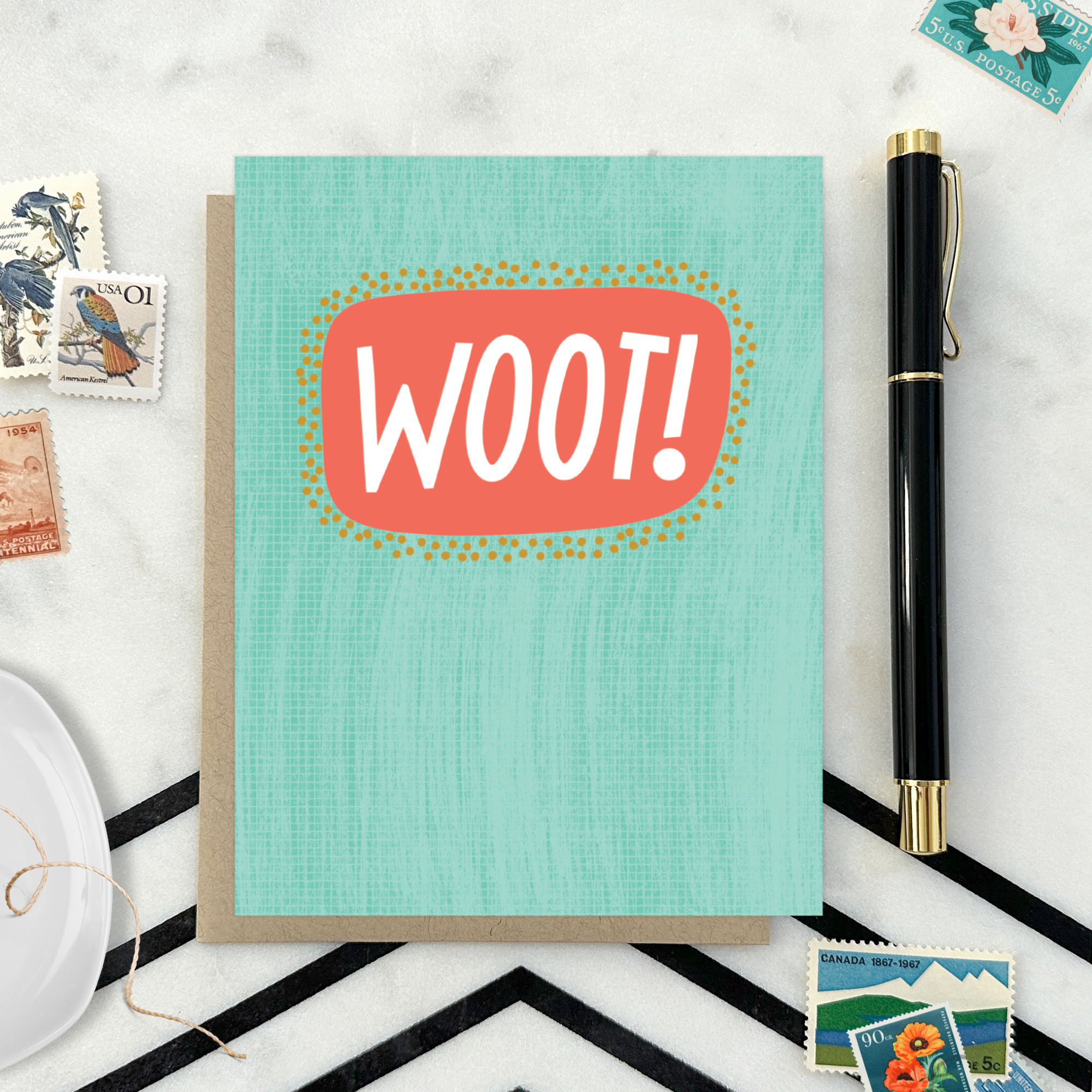 A congratulations greeting card with a hand-lettered word 'Woot!' written in bold, fun typography on a teal background with a textured appearance.