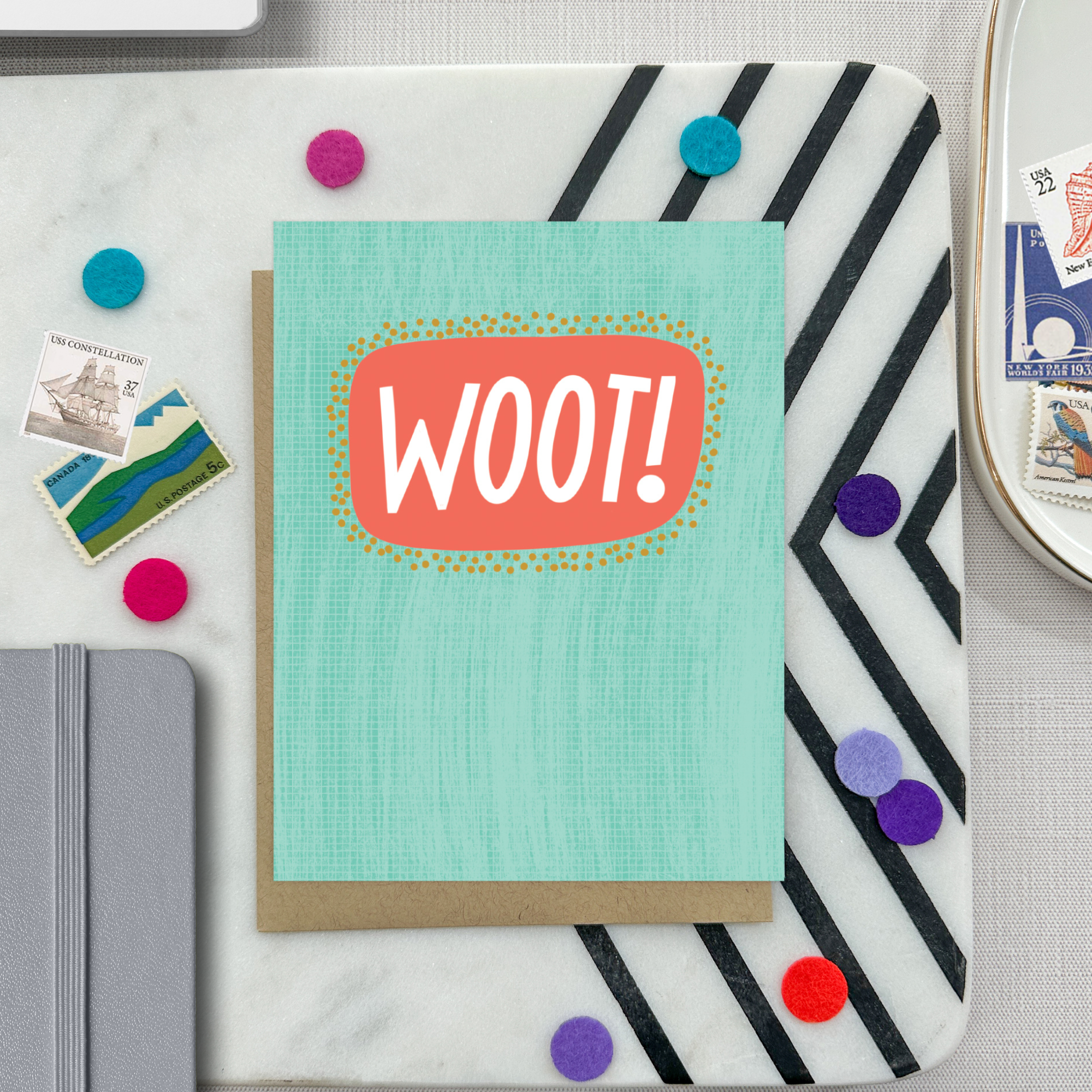 A congratulations greeting card with a hand-lettered word 'Woot!' written in bold, fun typography on a teal background with a textured appearance.