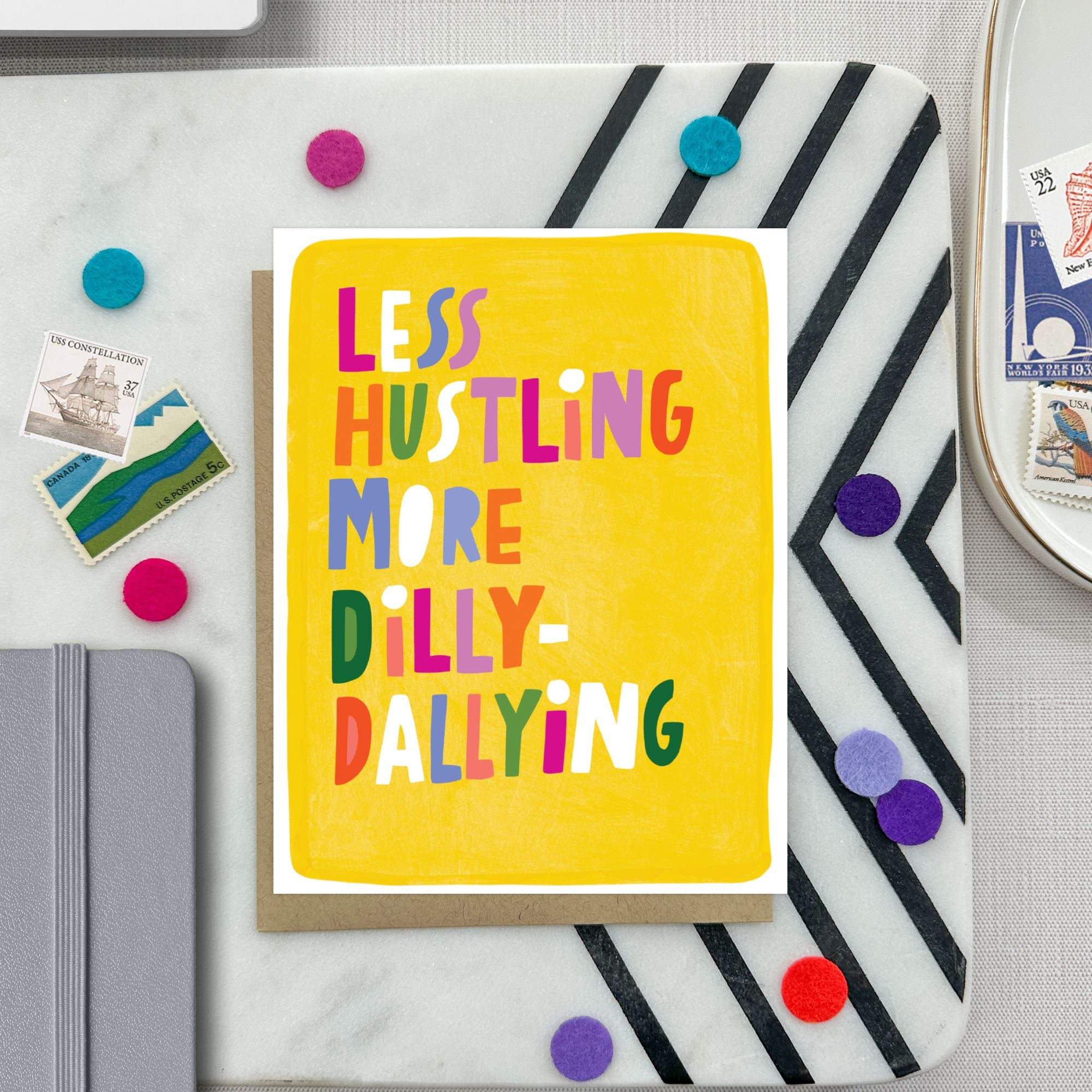 Greeting card with hand-lettered text “Less Hustling, More Dilly-Dallying” on bright yellow painterly background
