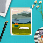 Greeting card with illustrated scenic landscape and a dumpster fire labeled “The World Right Now” with the caption “So… how are you?”