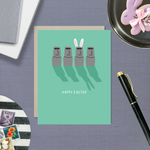 Easter greeting card with Easter island heads, one is wearing bunny ears with 'happy easter' text