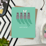 Easter greeting card with Easter island heads, one is wearing bunny ears with 'happy easter' text