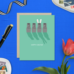 Easter greeting card with Easter island heads, one is wearing bunny ears with 'happy easter' text