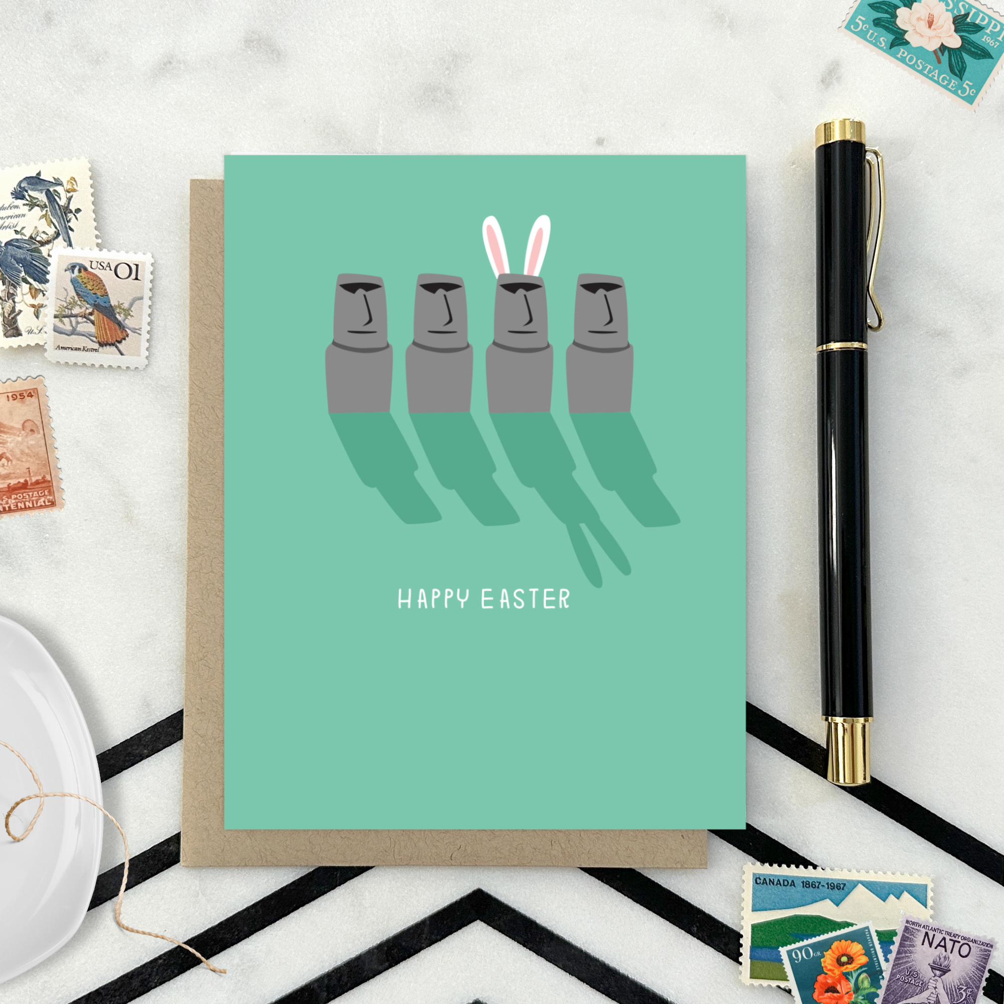 Easter greeting card with Easter island heads, one is wearing bunny ears with 'happy easter' text
