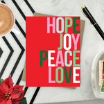 A red holiday greeting card with the words 'HOPE, JOY, PEACE, LOVE' stacked in a graphic design.