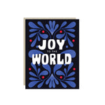 Christmas card with bold 'Joy to the World' lettering on a navy background framed by blue folk-art florals and red berries.