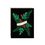 Christmas card with evergreen boughs and red berries framing a gold-lettered 'Joyeux Noel' banner on a black background.