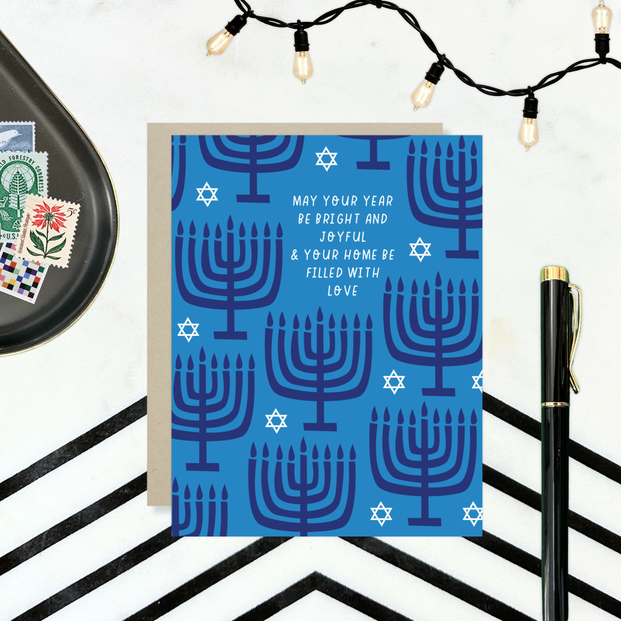 Hannukah greeting card with menorahs and stars of David scattered with 'may your year be bright and joyful & your home be filled with love' text