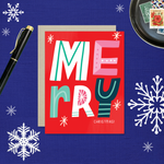 A festive Christmas greeting card with the word 'Merry' written in colorful, decorative lettering on a red background, with 'Christmas' written below.