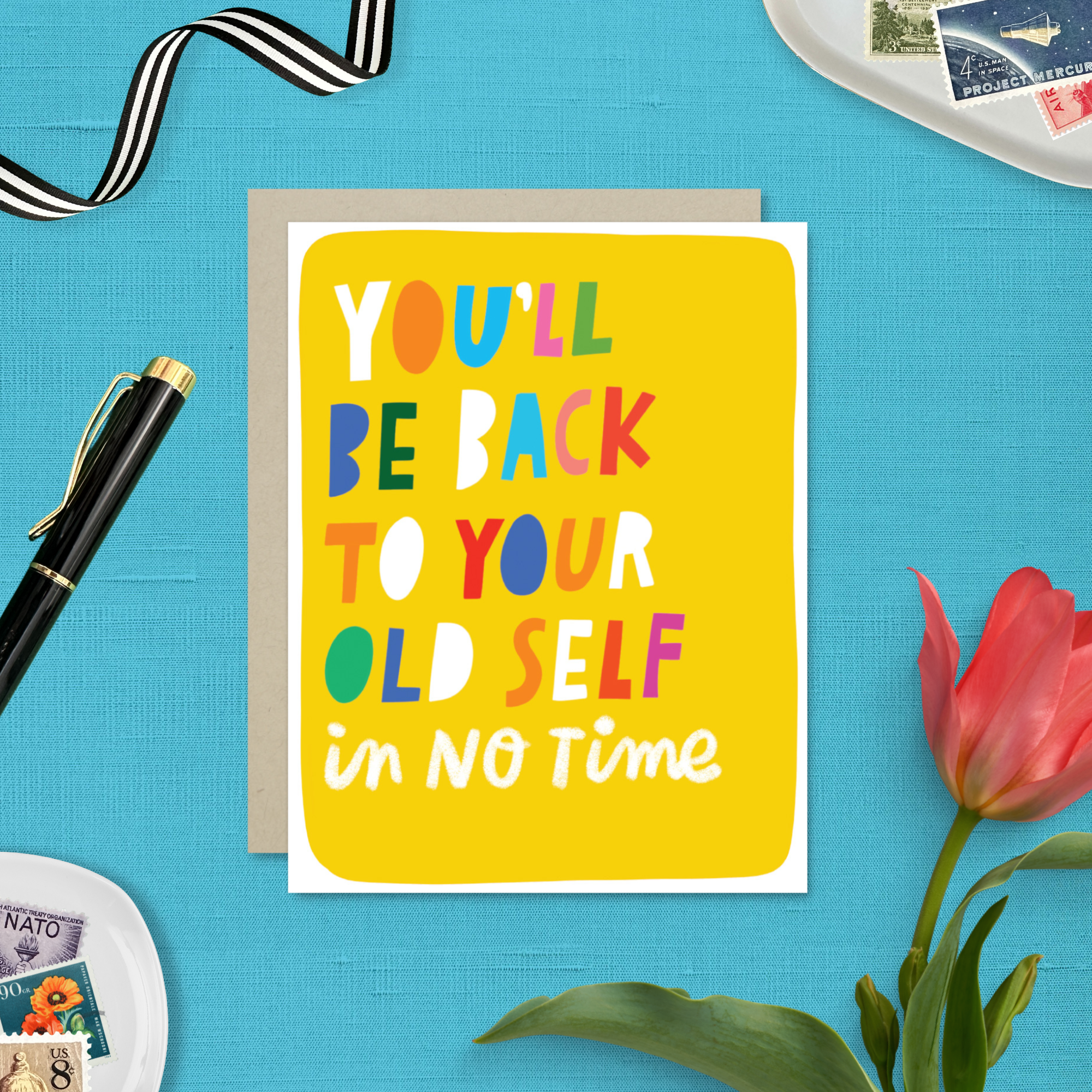 Get well colorful greeting card with motivational text on a blue background with stationery items.