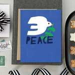  hand-painted holiday reeting card with a blue background featuring a white bird and the word 'PEACE' in capital letters.
