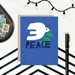  hand-painted holiday reeting card with a blue background featuring a white bird and the word 'PEACE' in capital letters.