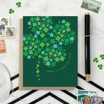A st. patricks day greeting card with a pattern of tiny illustrated shamrocks arranged in the shape of a larger four-leaf clover, and the text 'Happy St. Patrick's Day' 