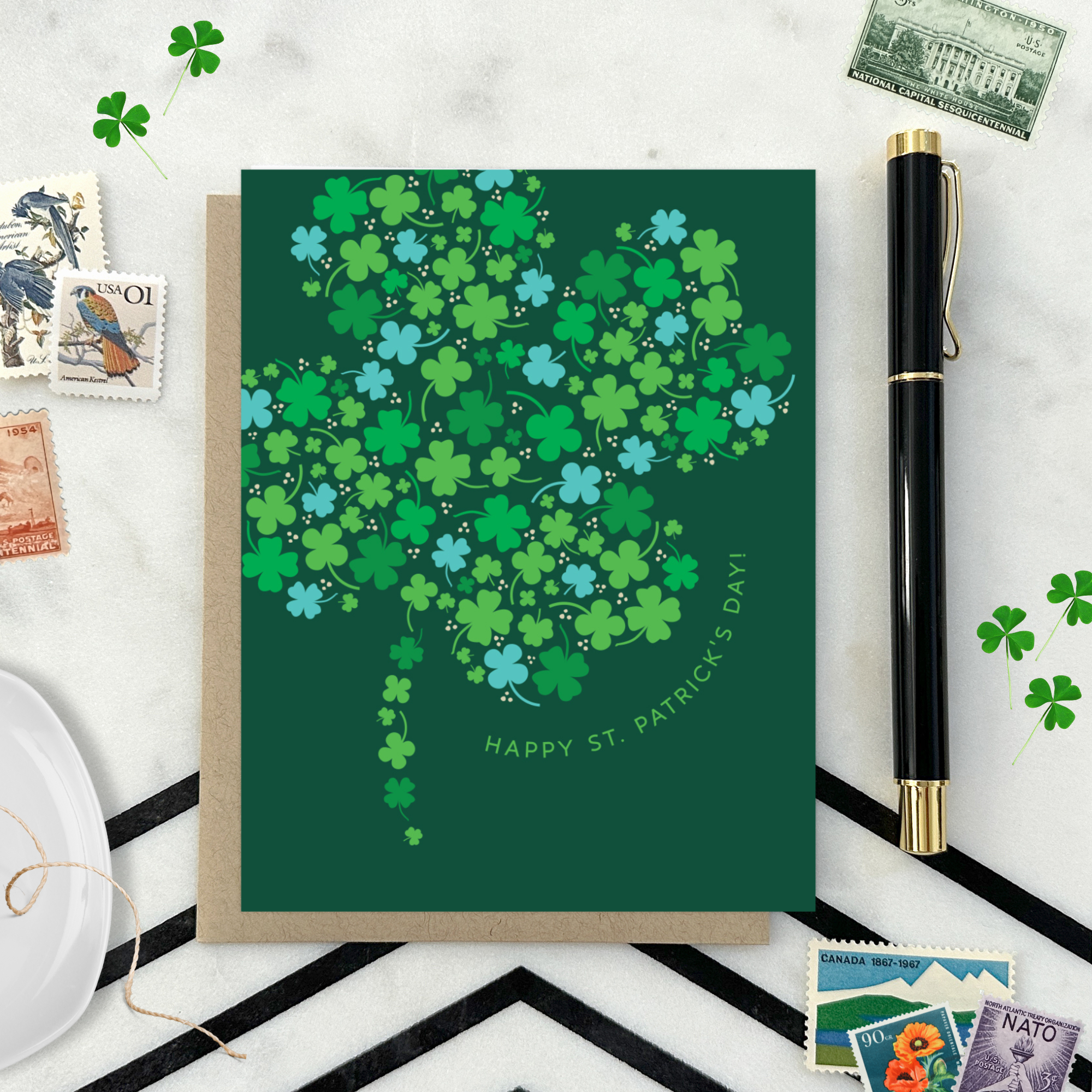 A st. patricks day greeting card with a pattern of tiny illustrated shamrocks arranged in the shape of a larger four-leaf clover, and the text 'Happy St. Patrick's Day' 