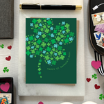 A st. patricks day greeting card with a pattern of tiny illustrated shamrocks arranged in the shape of a larger four-leaf clover, and the text 'Happy St. Patrick's Day' 